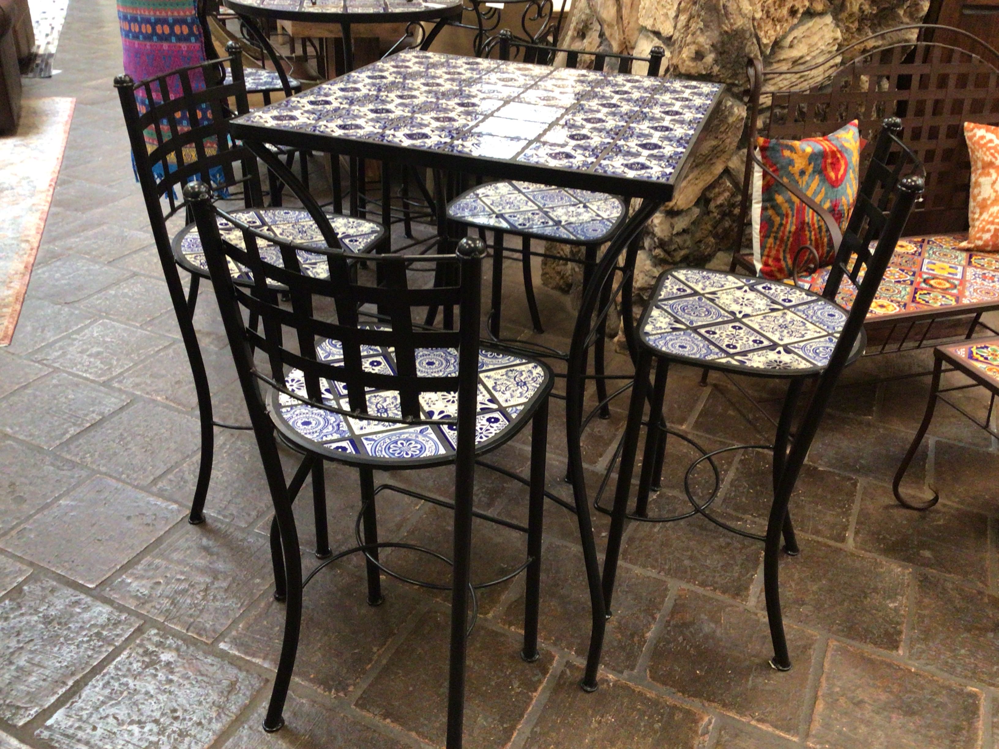 Outdoor patio set with tiled table and chairs on a stone patio