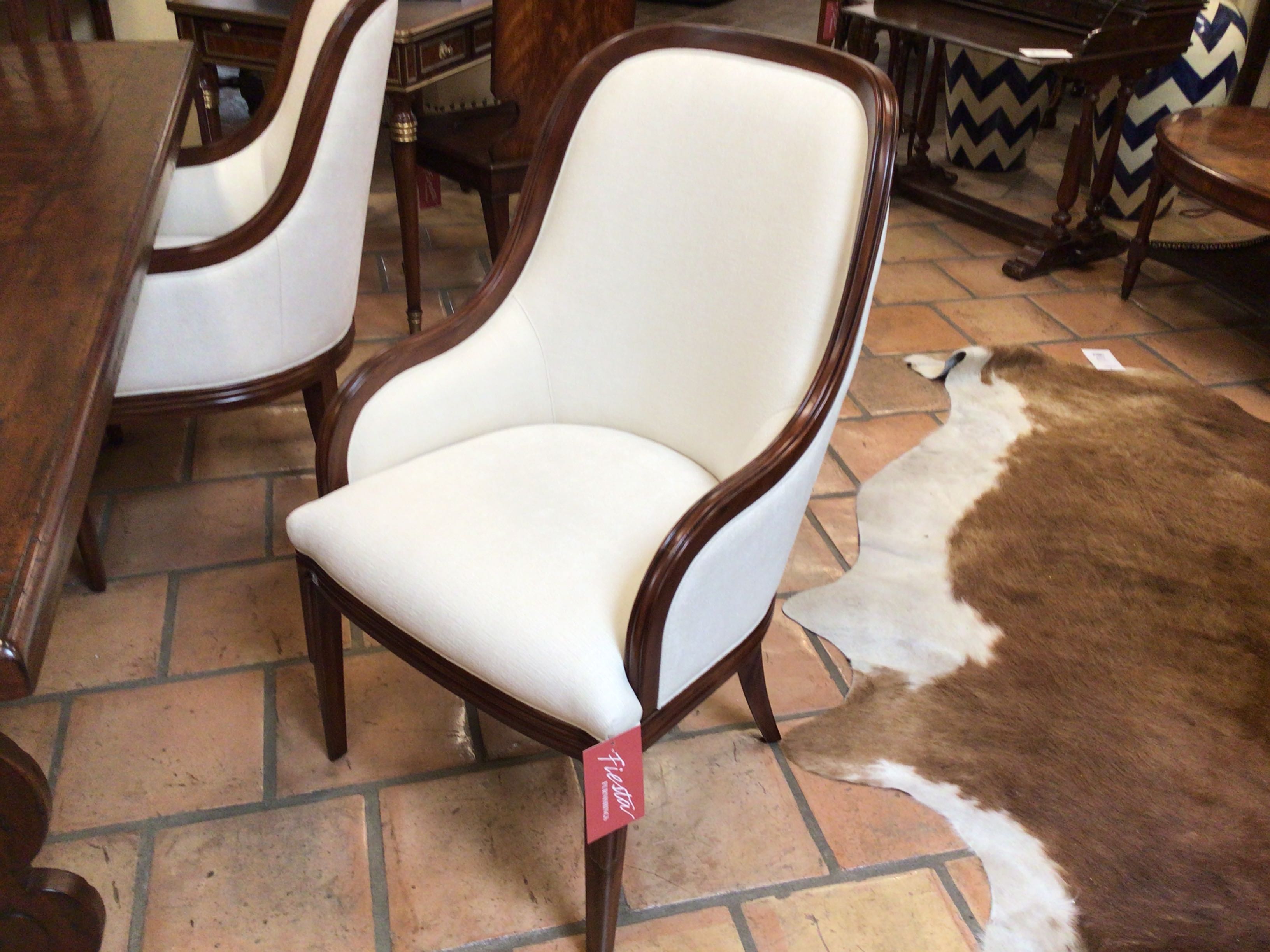 White chair with wooden frame on a tiled floor, surrounded by furniture.