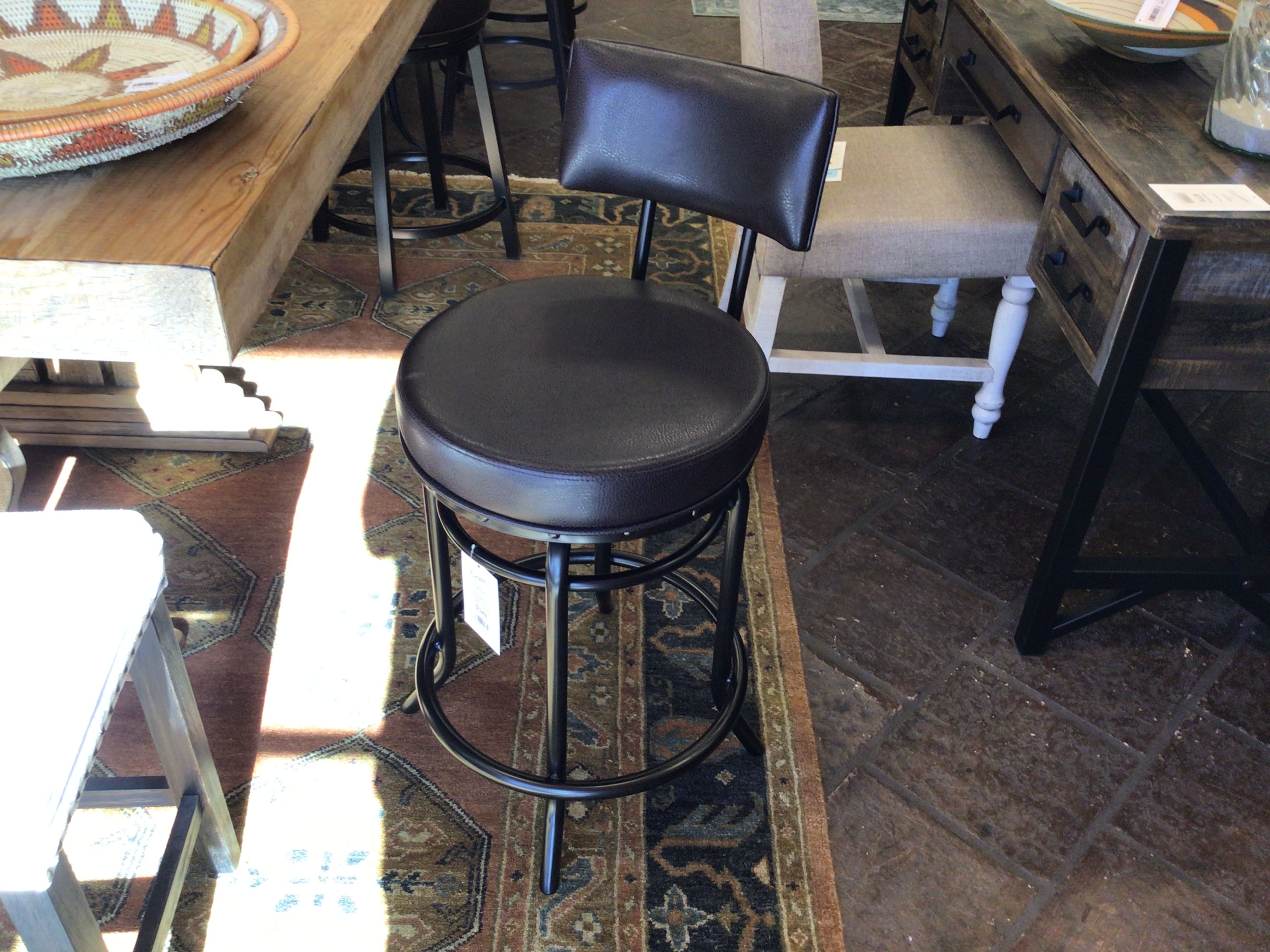 Black bar stool in a store setting with tables and chairs in the background.