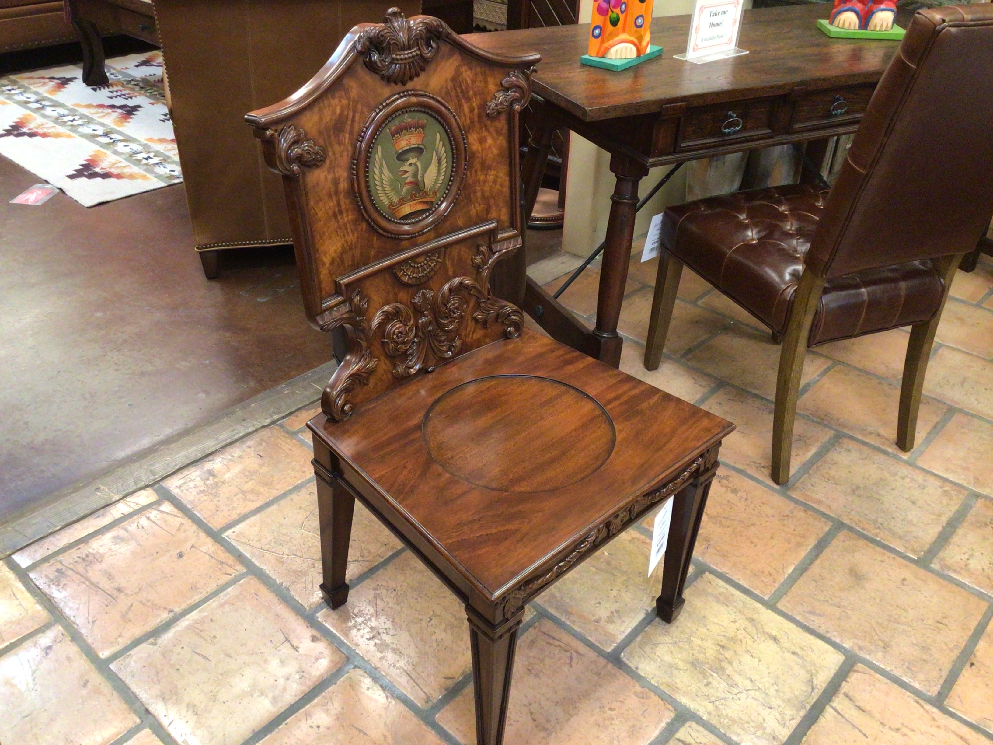 Decorative wooden chair with intricate carvings on a tiled floor.