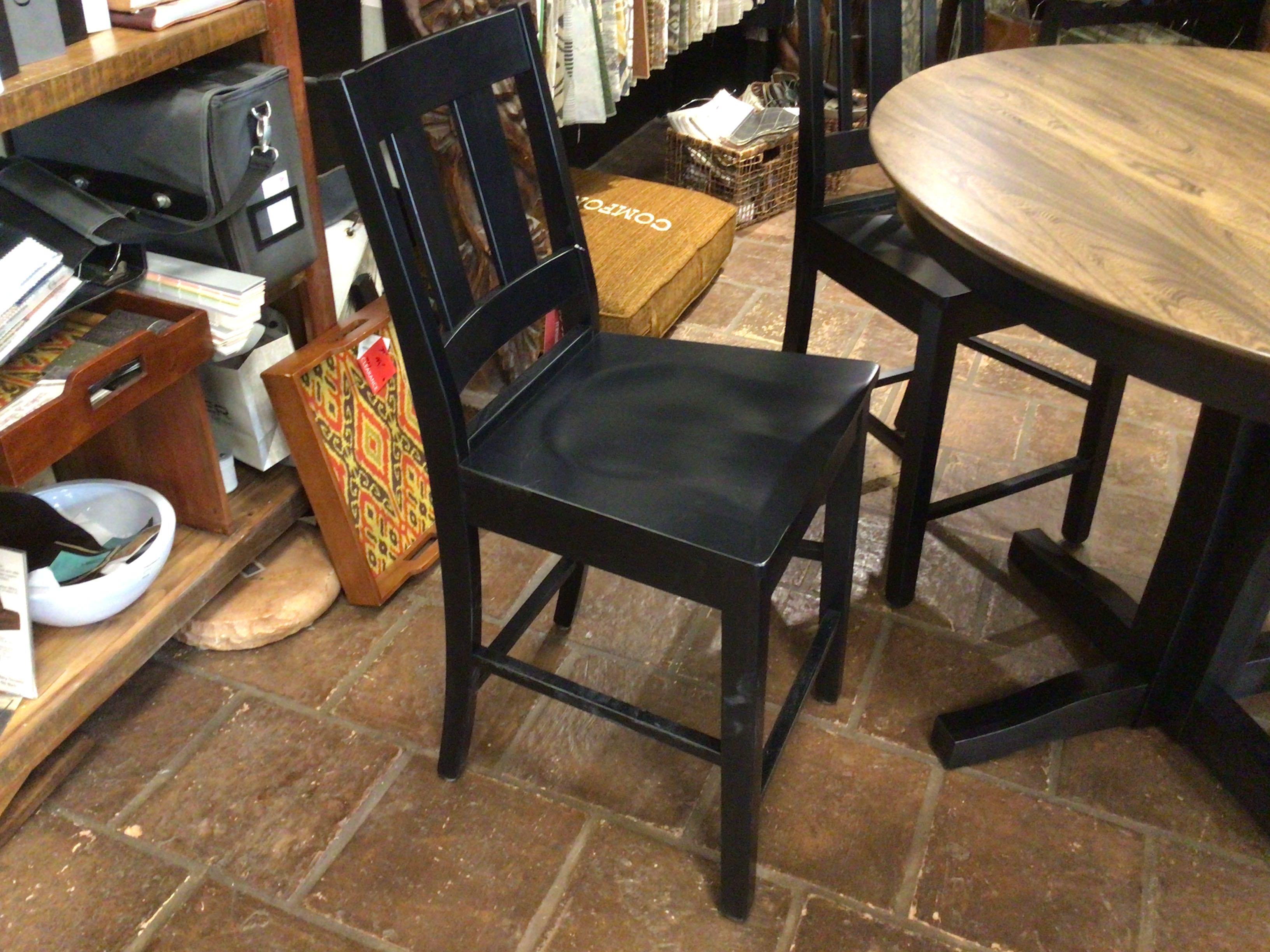 Black chair in a room with a wooden floor and furniture.