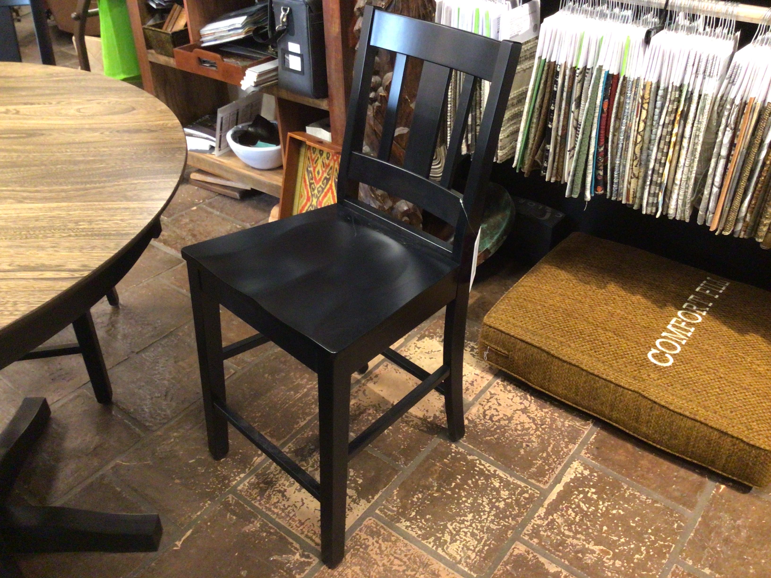 Black chair in a room with a round wooden table and a doormat on the floor.