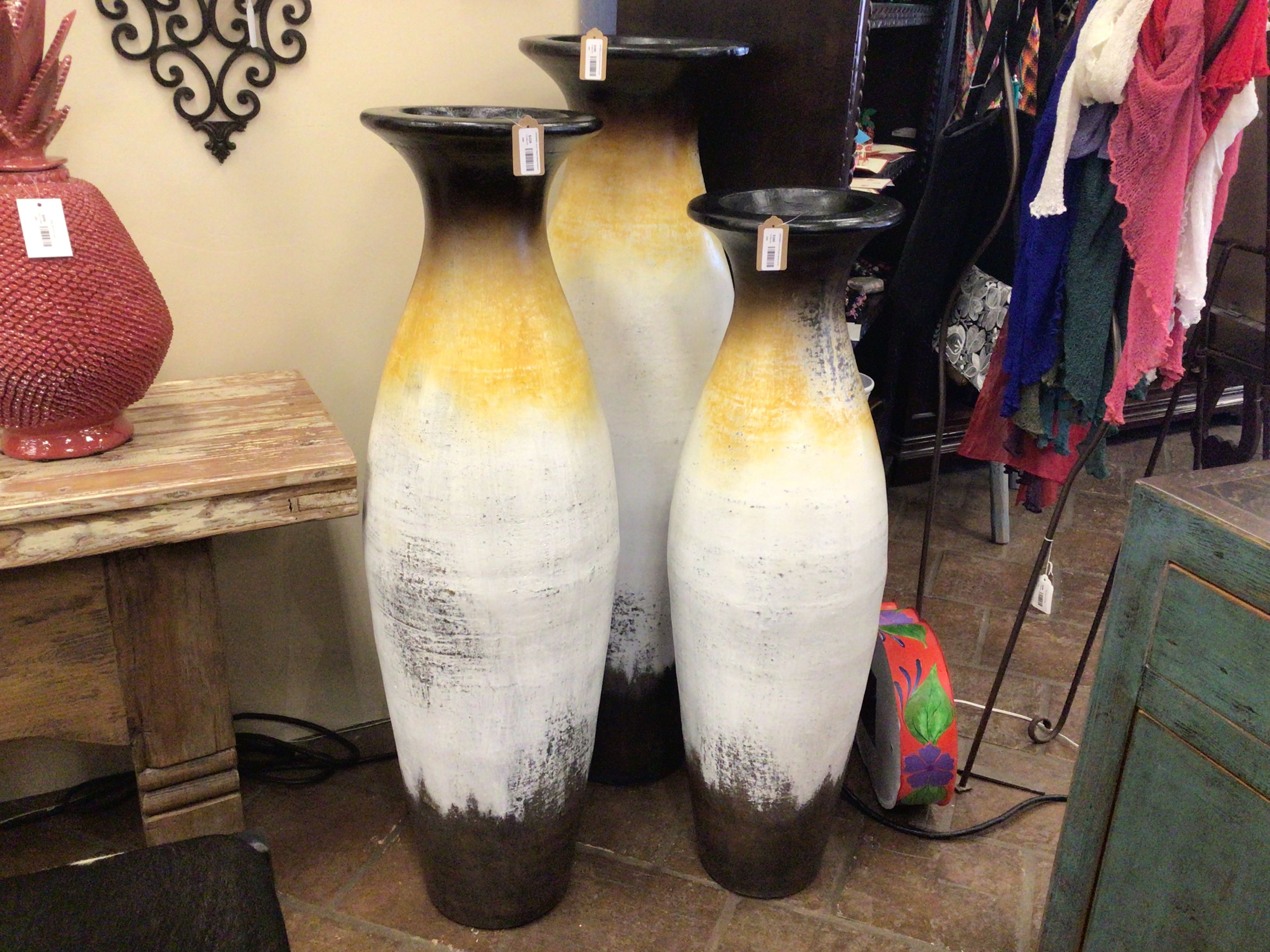 Three tall ceramic vases with black and white gradient design in a store setting.