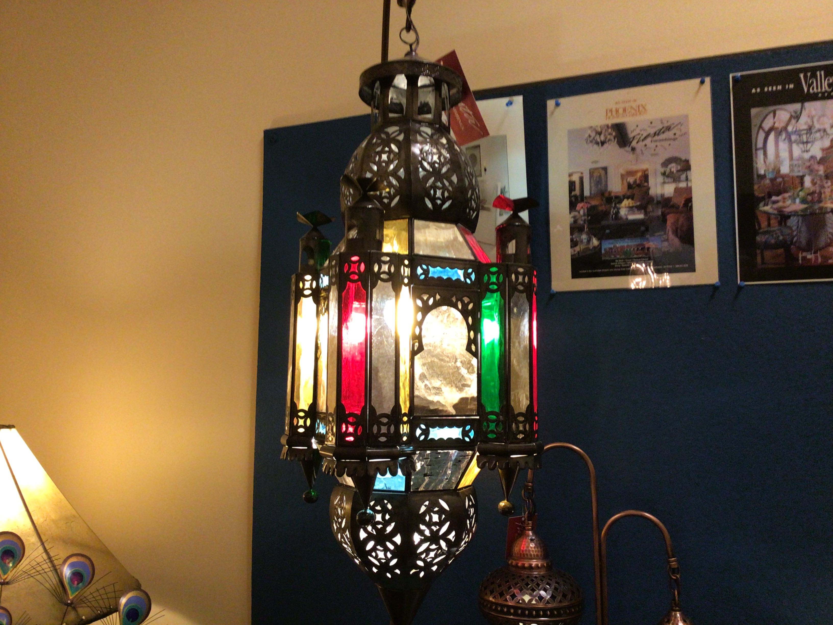 Decorative hanging lamp with colorful glass panels in a room with posters on the wall.