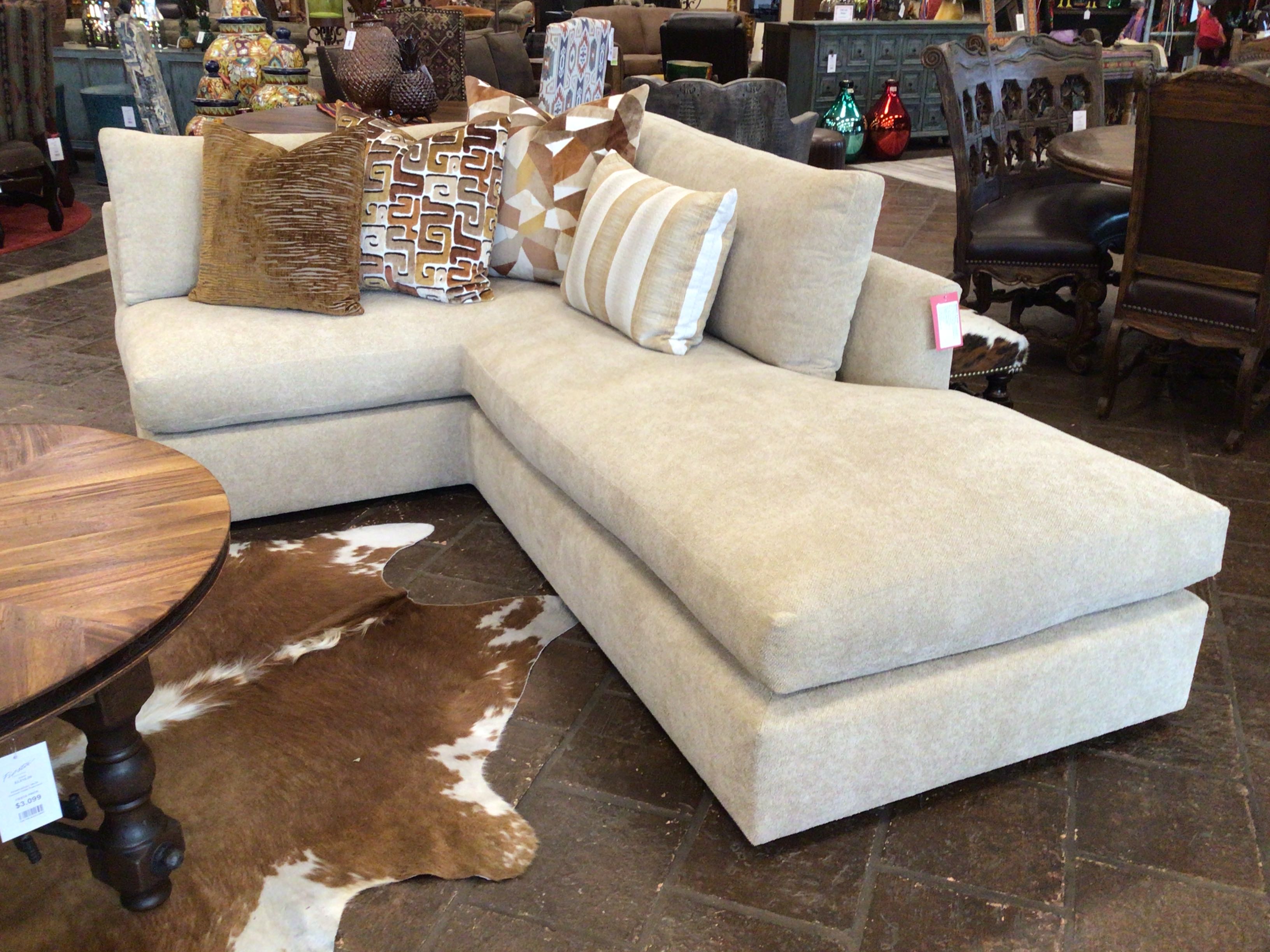 A Sand colored L shape sofa with 4 pillows in a showroom setting. 