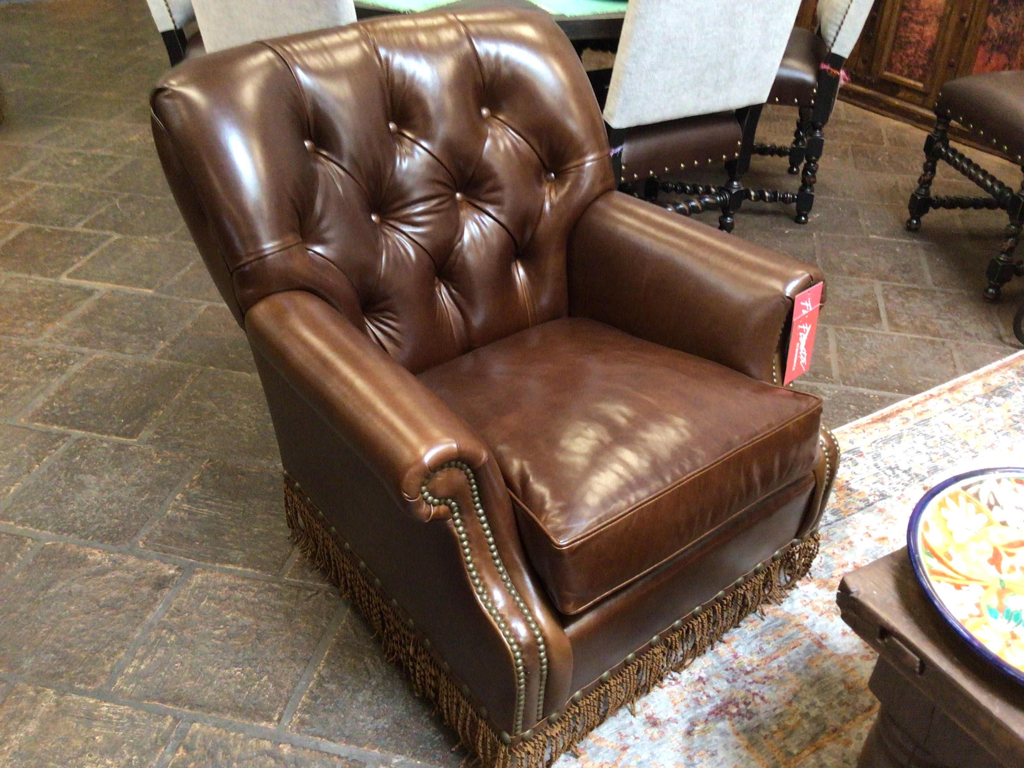 Brown leather armchair in a room with a patterned rug and furniture.