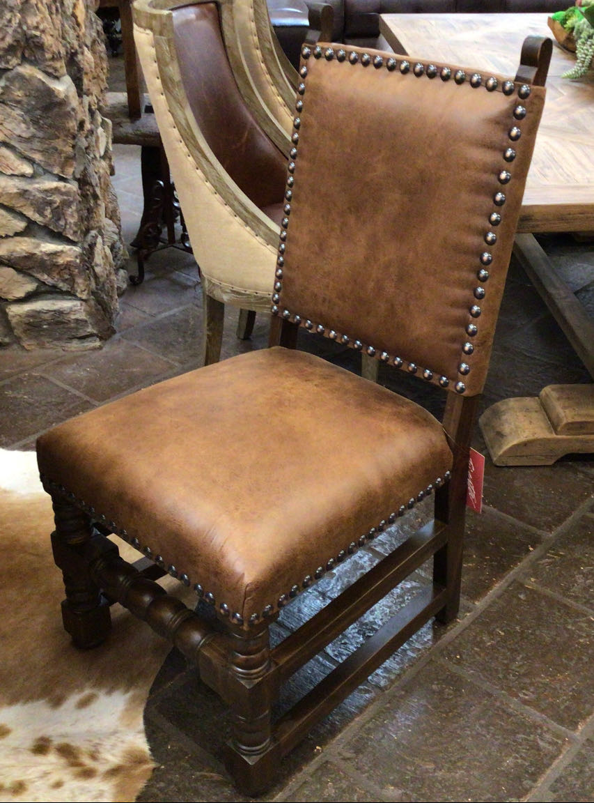 Brown leather chair with nailhead trim in a rustic setting