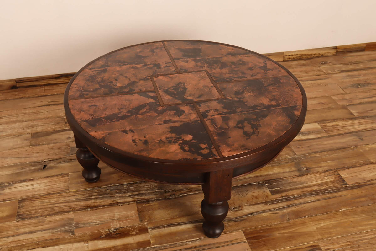 Round wooden table with a patchwork design on a wooden floor.
