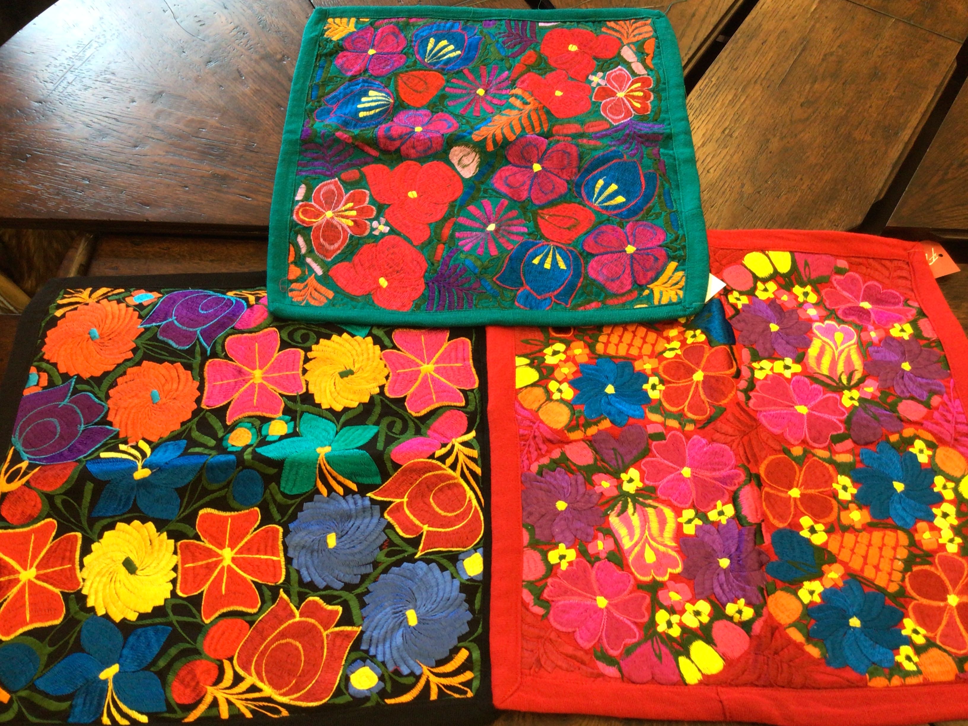 Three colorful floral-patterned coasters on a wooden surface