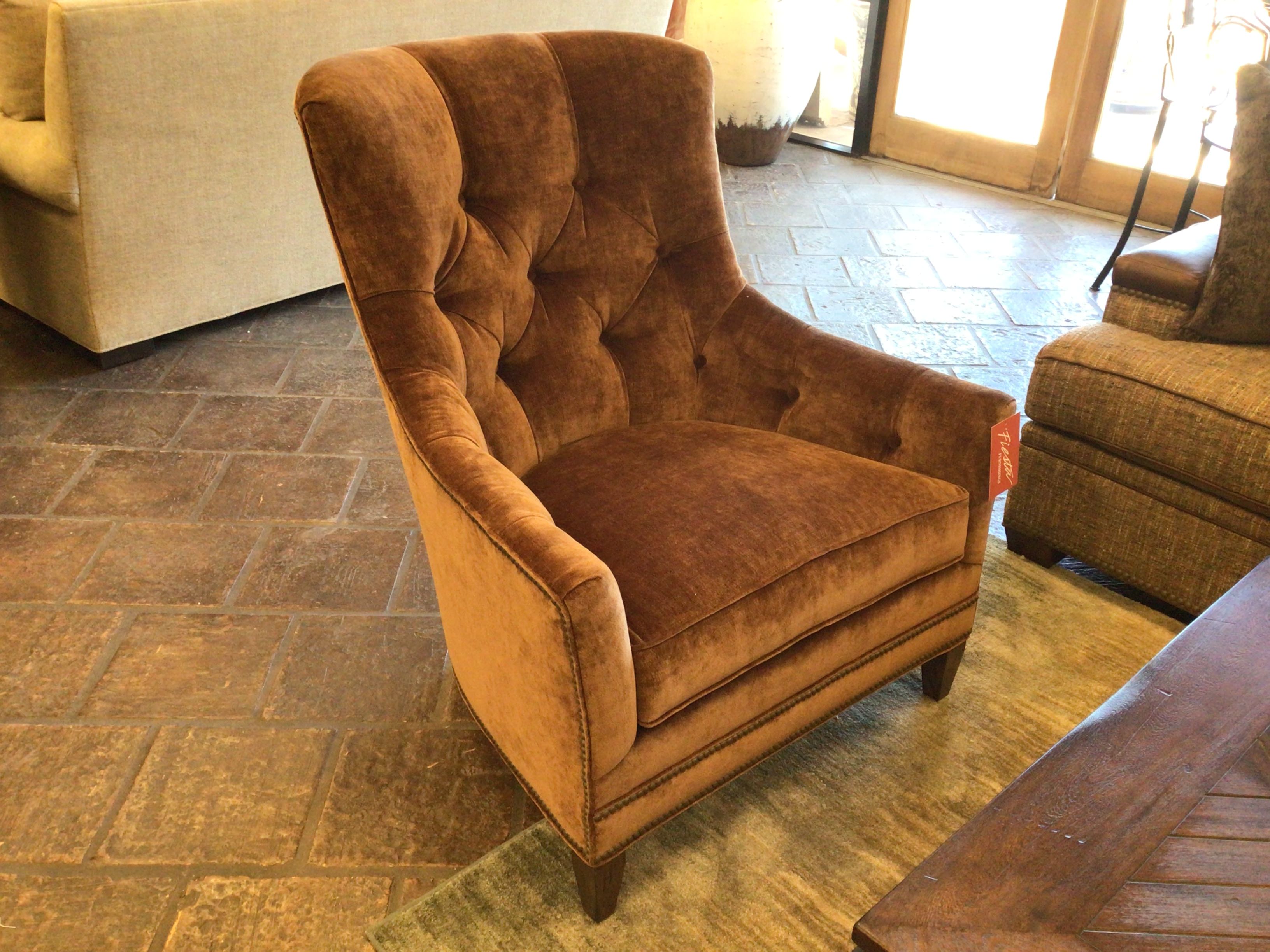 Brown upholstered armchair in a room with tiled floor and other furniture.