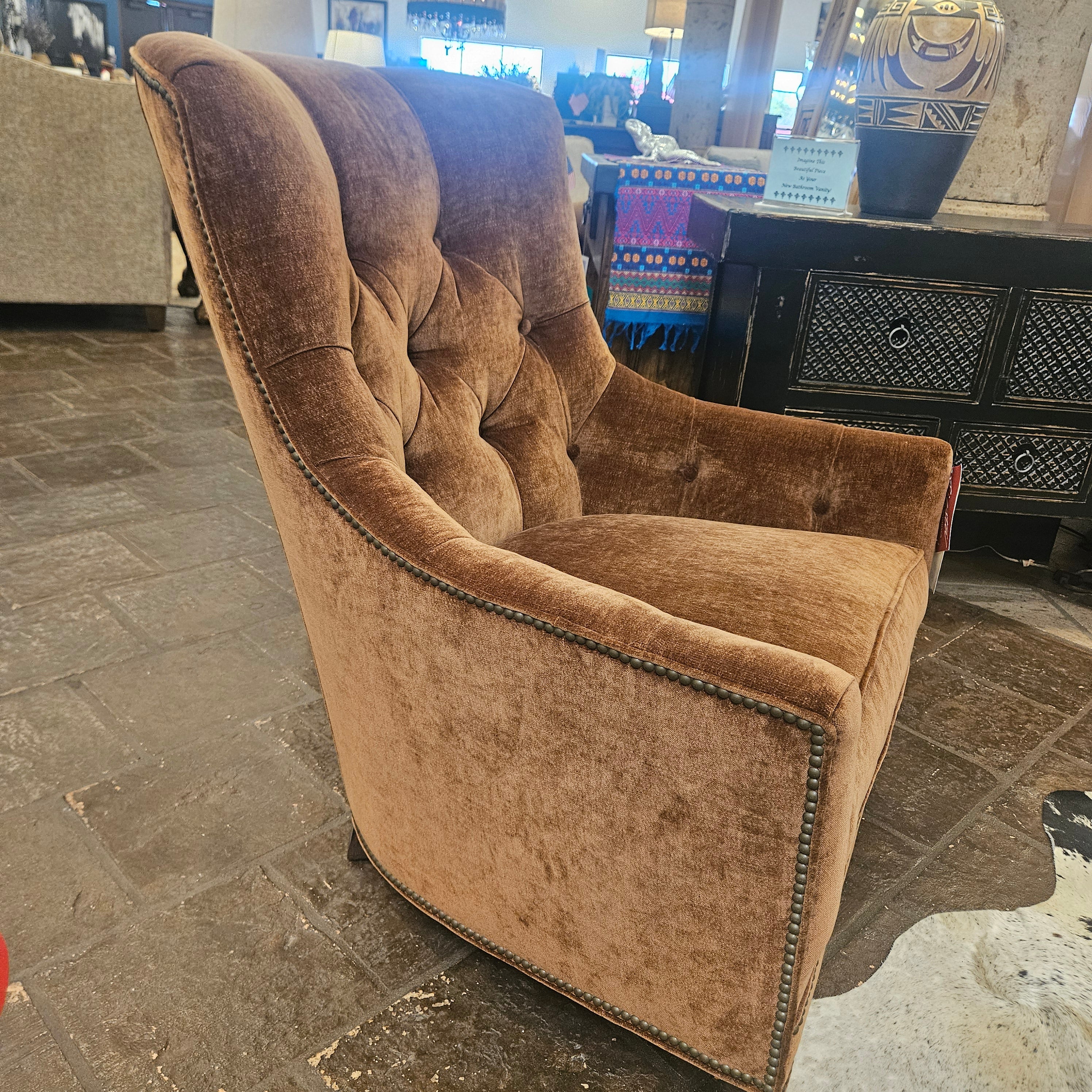 Brown fabric upholstered armchair in a room with a stone floor and decorative items.