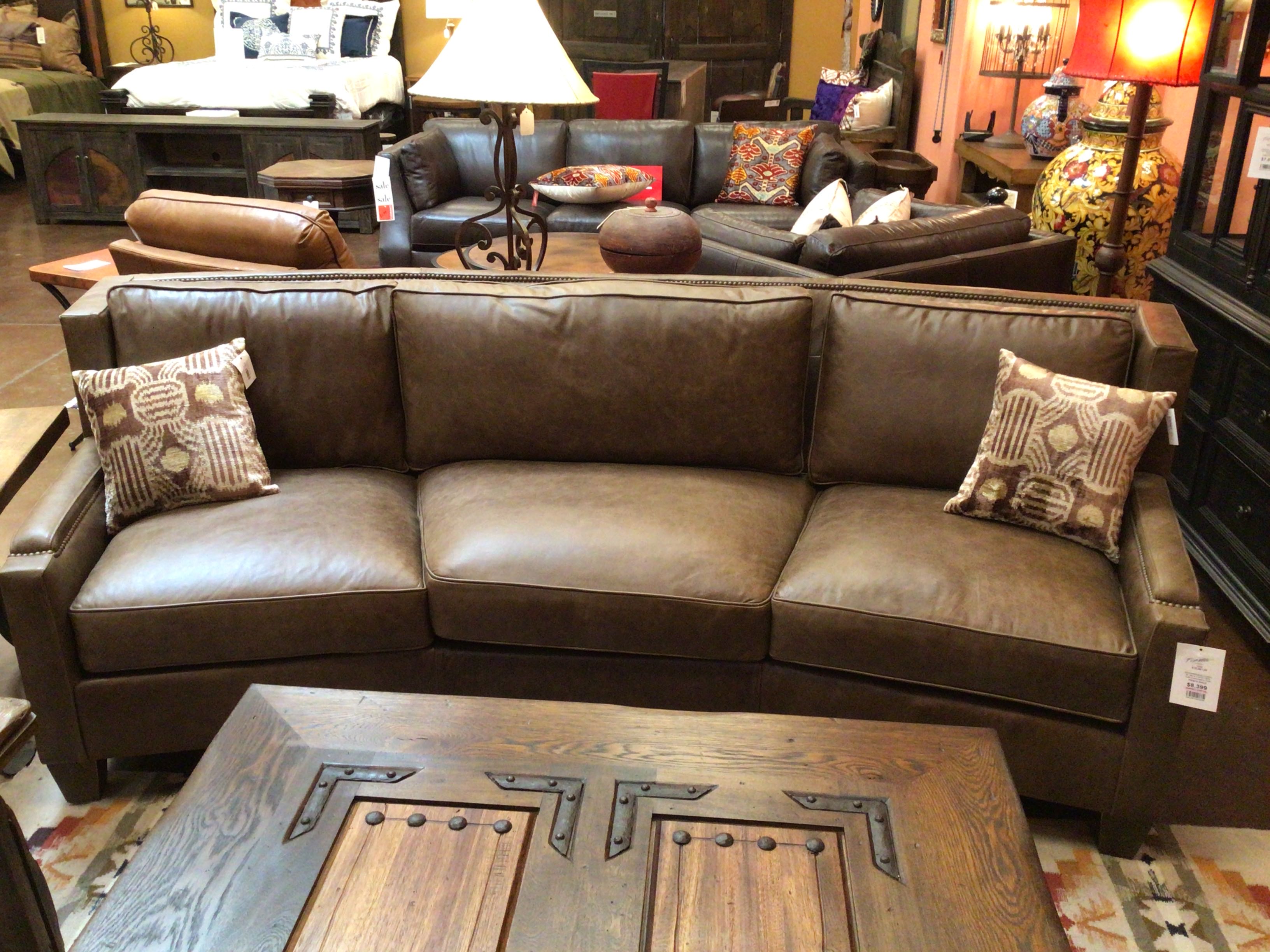 Brown leather sectional sofa with decorative pillows in a furniture store setting.