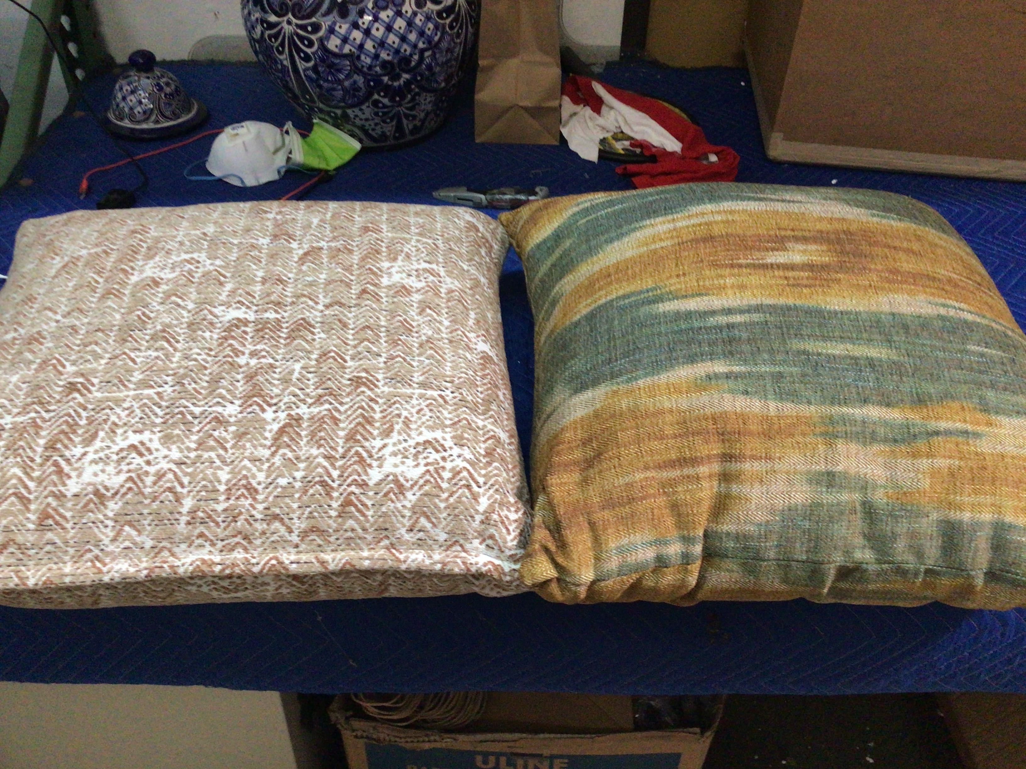 Two fabric samples on a blue surface with various items in the background