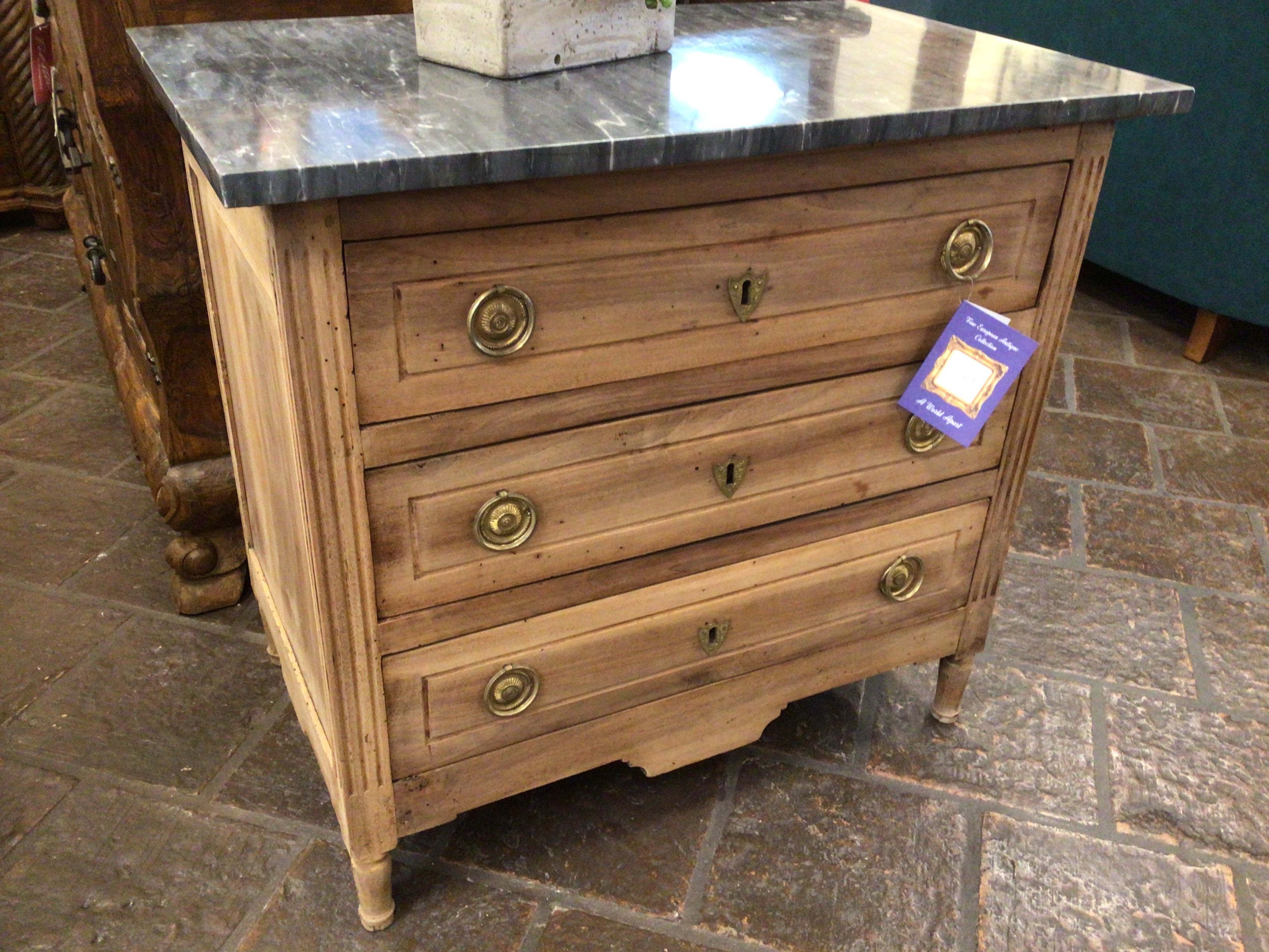 Wooden dresser with marble top on a stone floor
