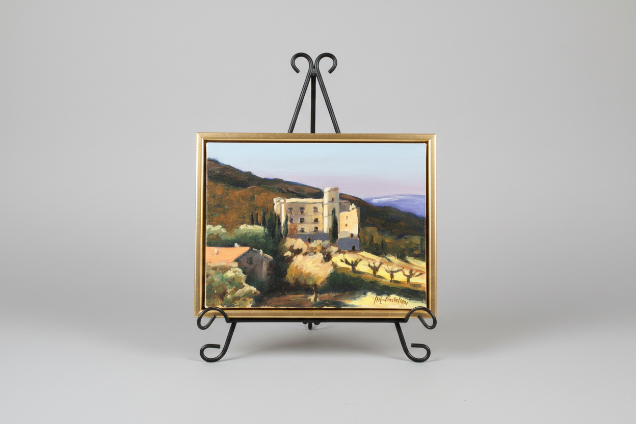 Painting of a castle scene on an easel with a gray background