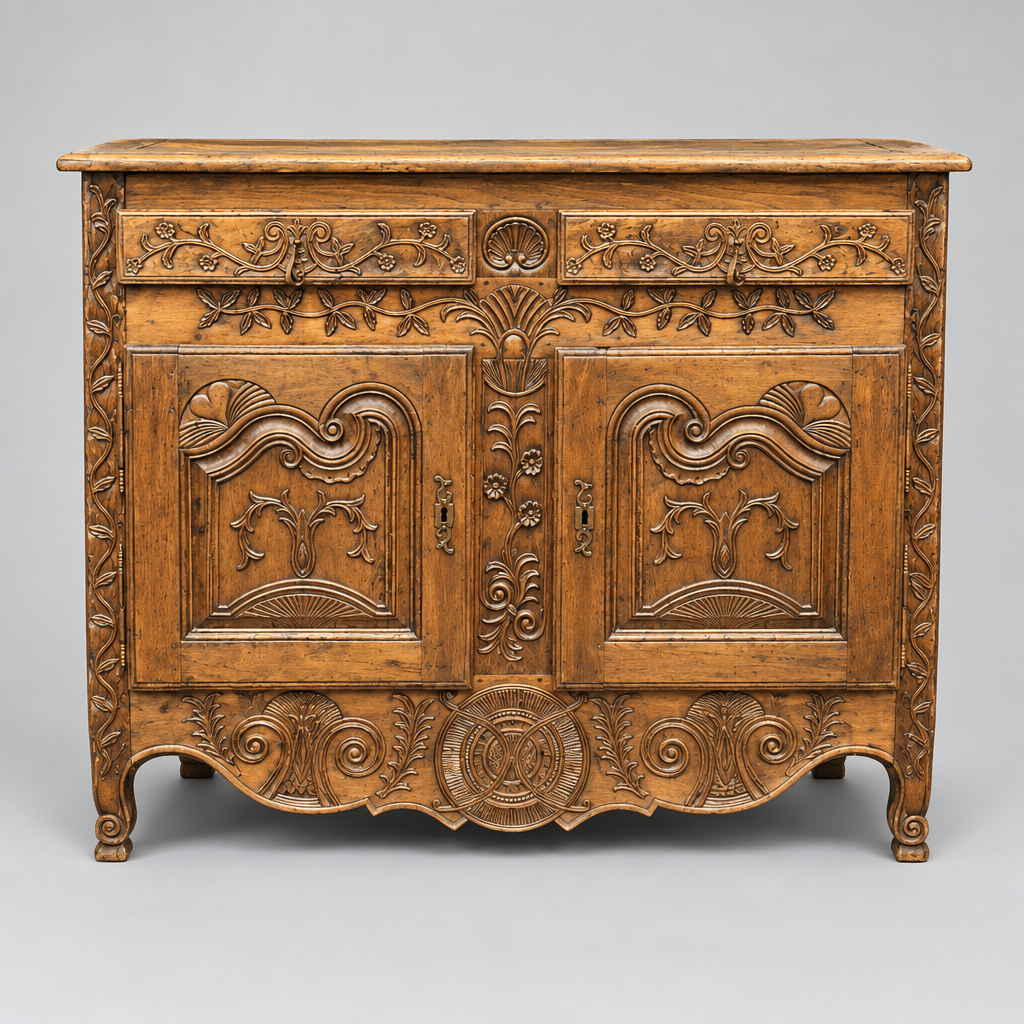 An ornate antique wooden chest or cabinet with intricate carved floral and scroll motifs, featuring two doors, decorative panels, and carved legs, photographed against a neutral gray studio background.