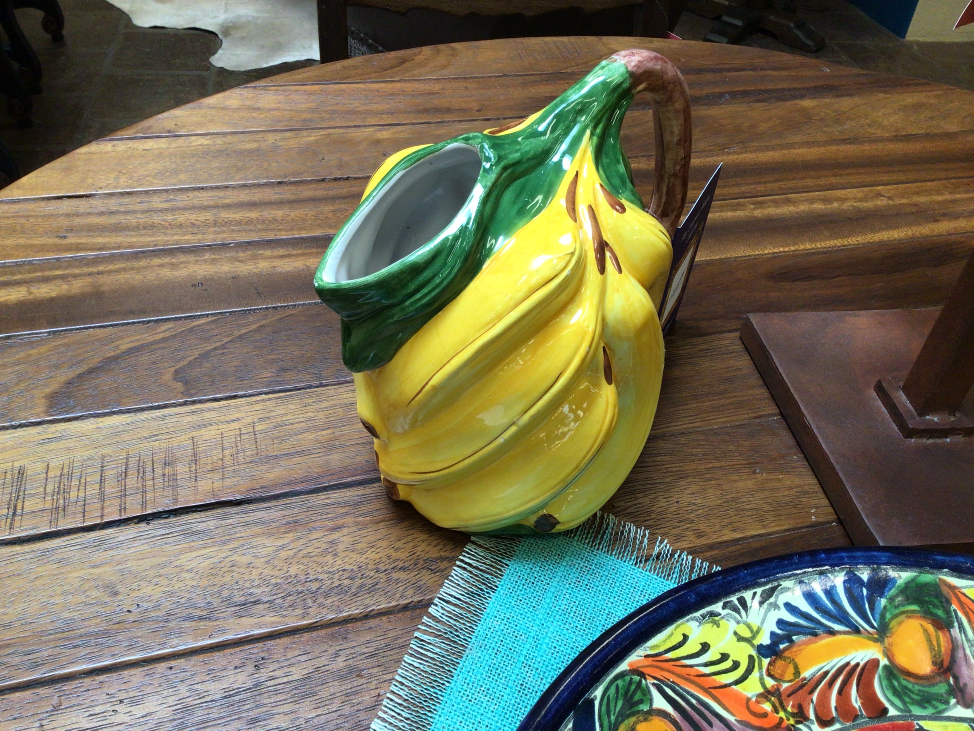 Ceramic lemon-shaped container on a wooden table with a colorful plate and napkin.