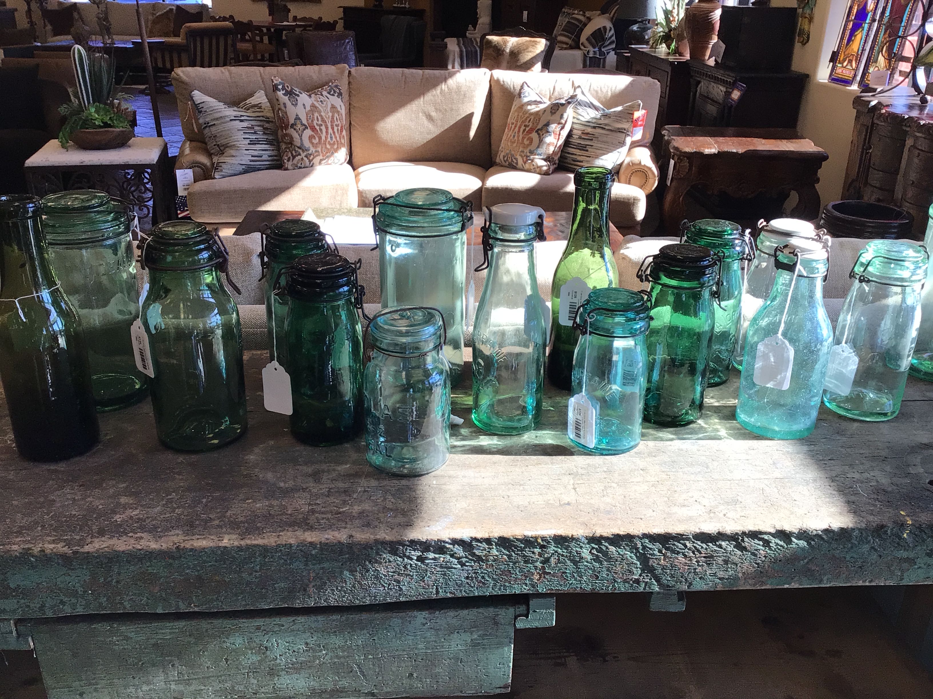 Collection of green glass bottles on a stone surface with a blurred indoor background