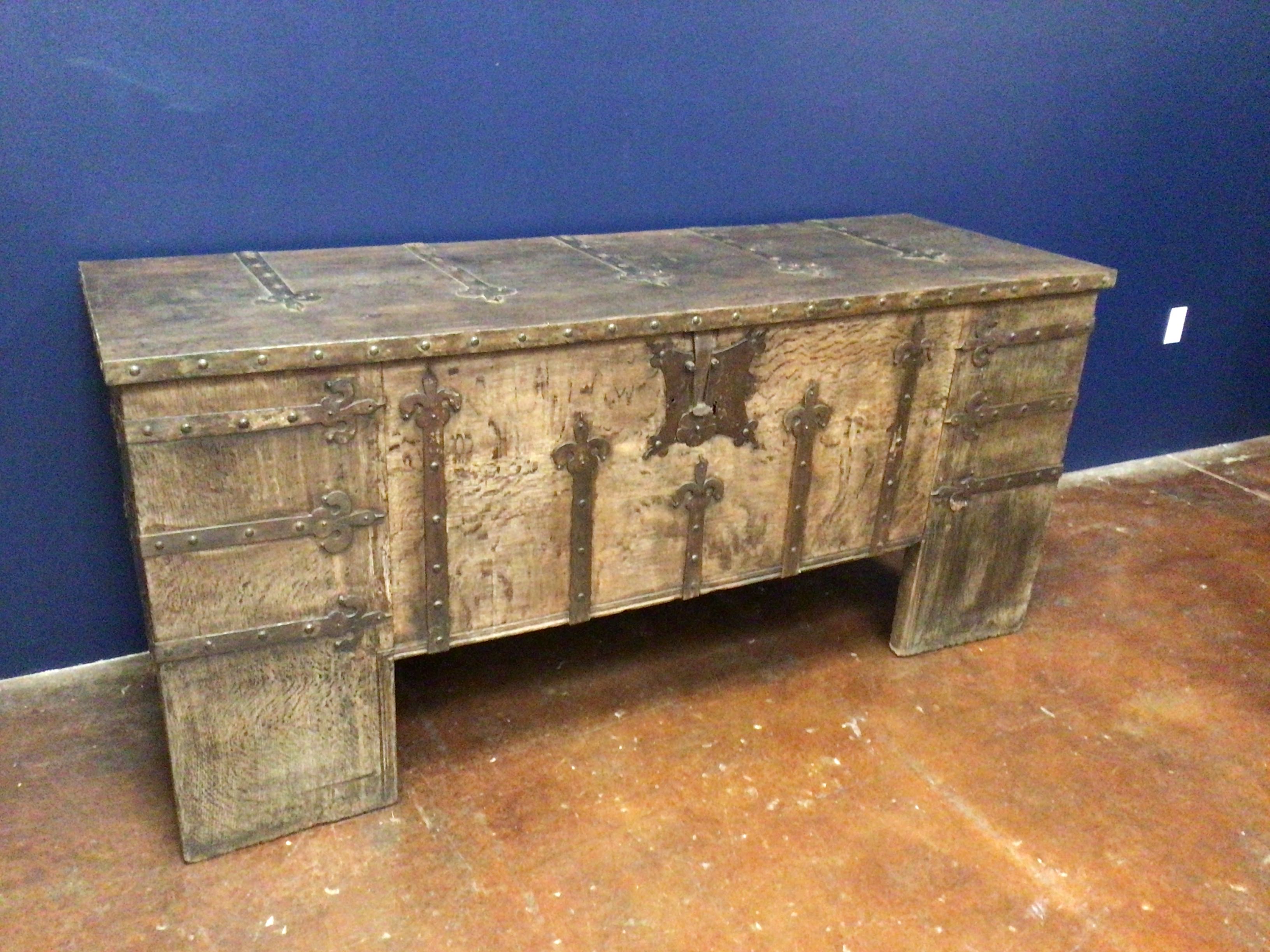 Wooden chest with metal accents against a blue wall