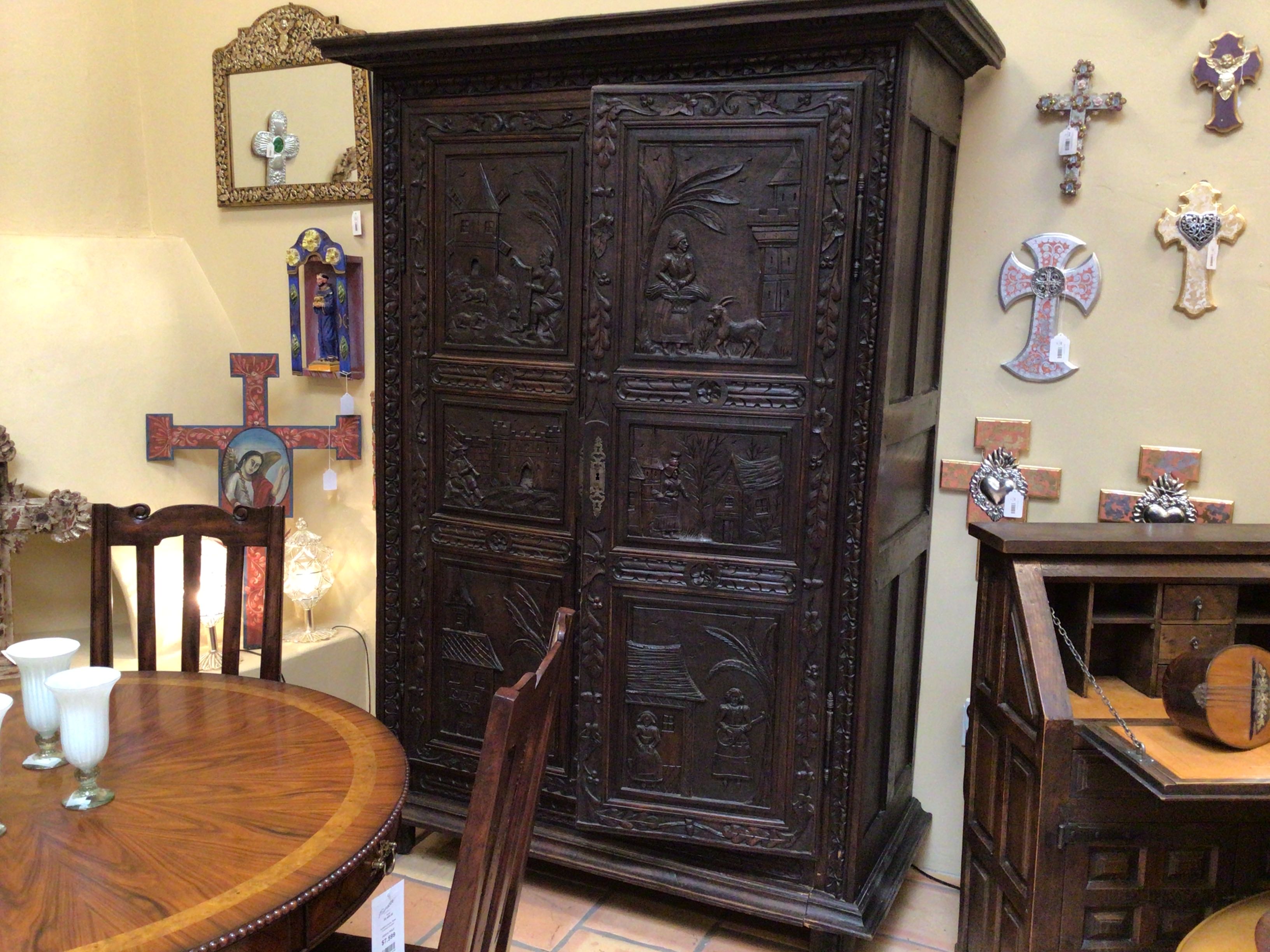 Decorative wooden cabinet with intricate carvings in a room with religious decor.