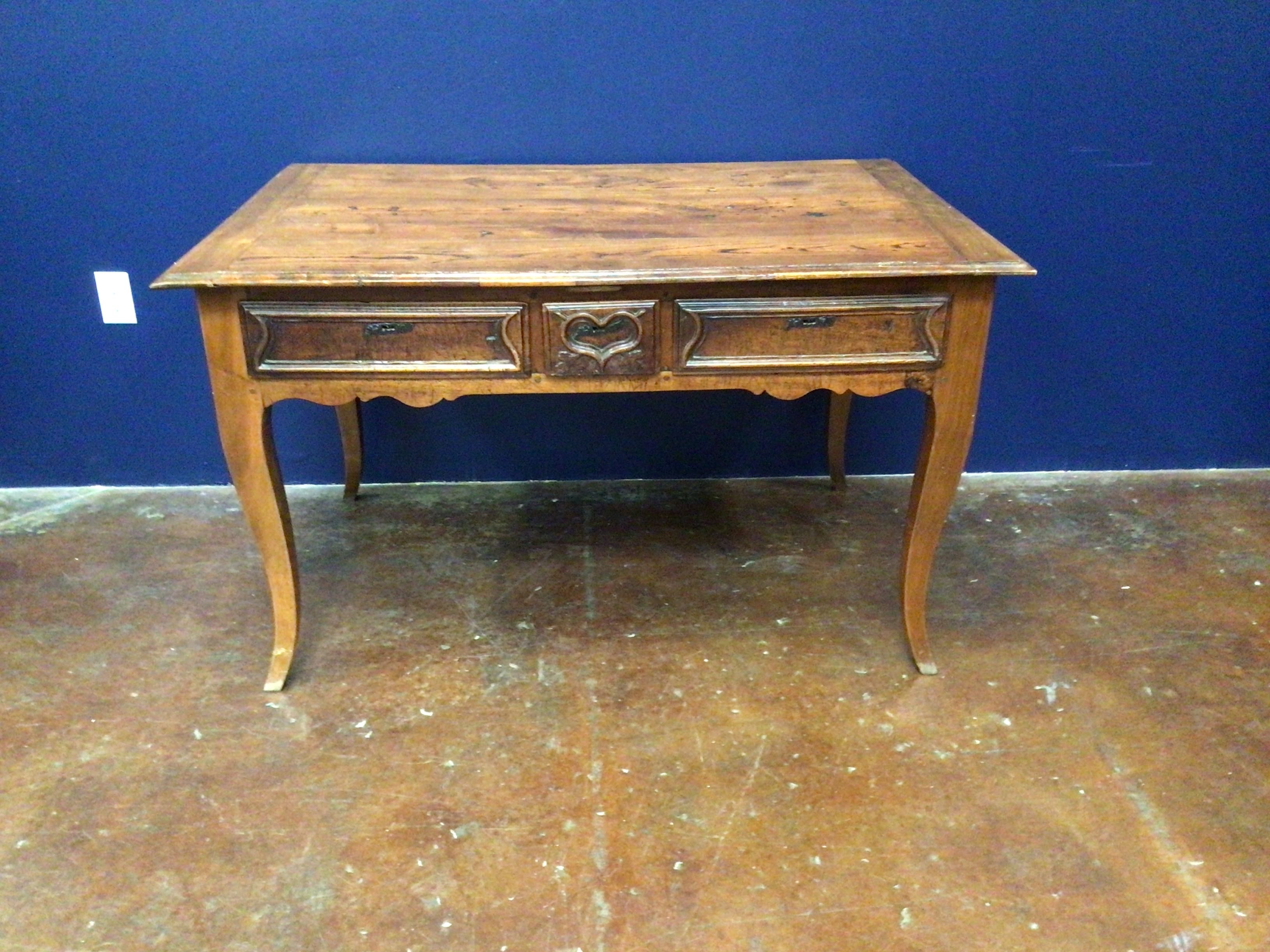 Wooden desk with decorative carvings on a blue wall background
