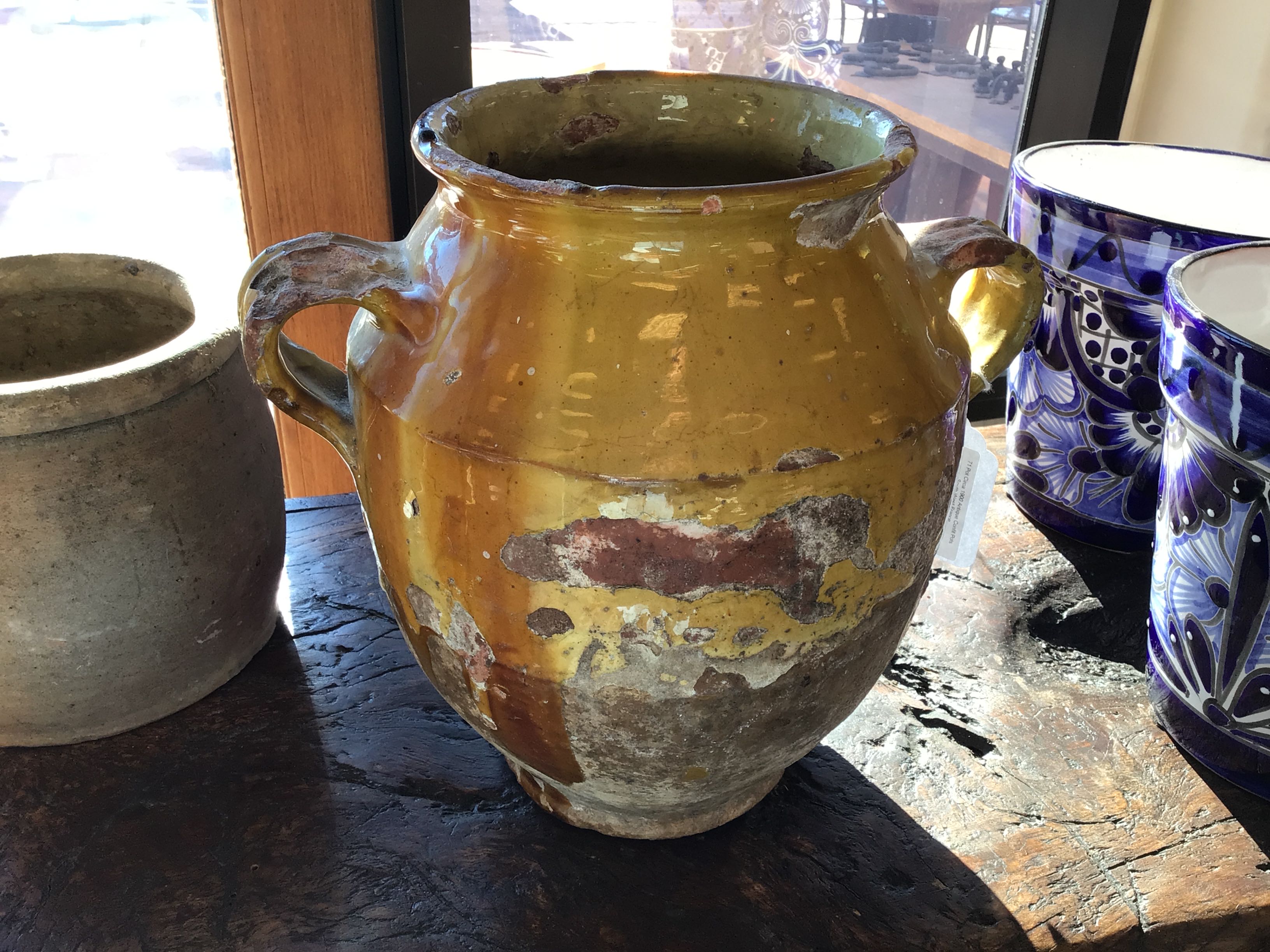 Yellow ceramic vase with handles on a wooden surface