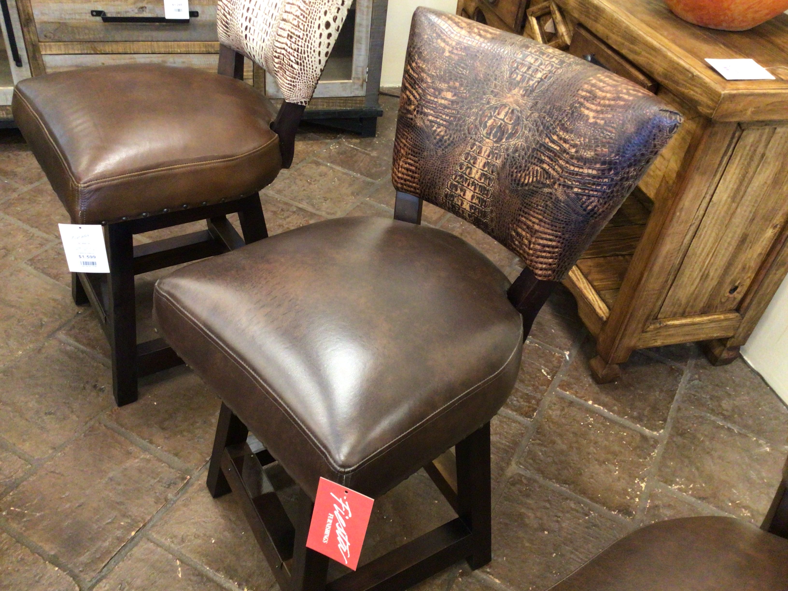 Brown leather stools with wooden legs on a stone floor.