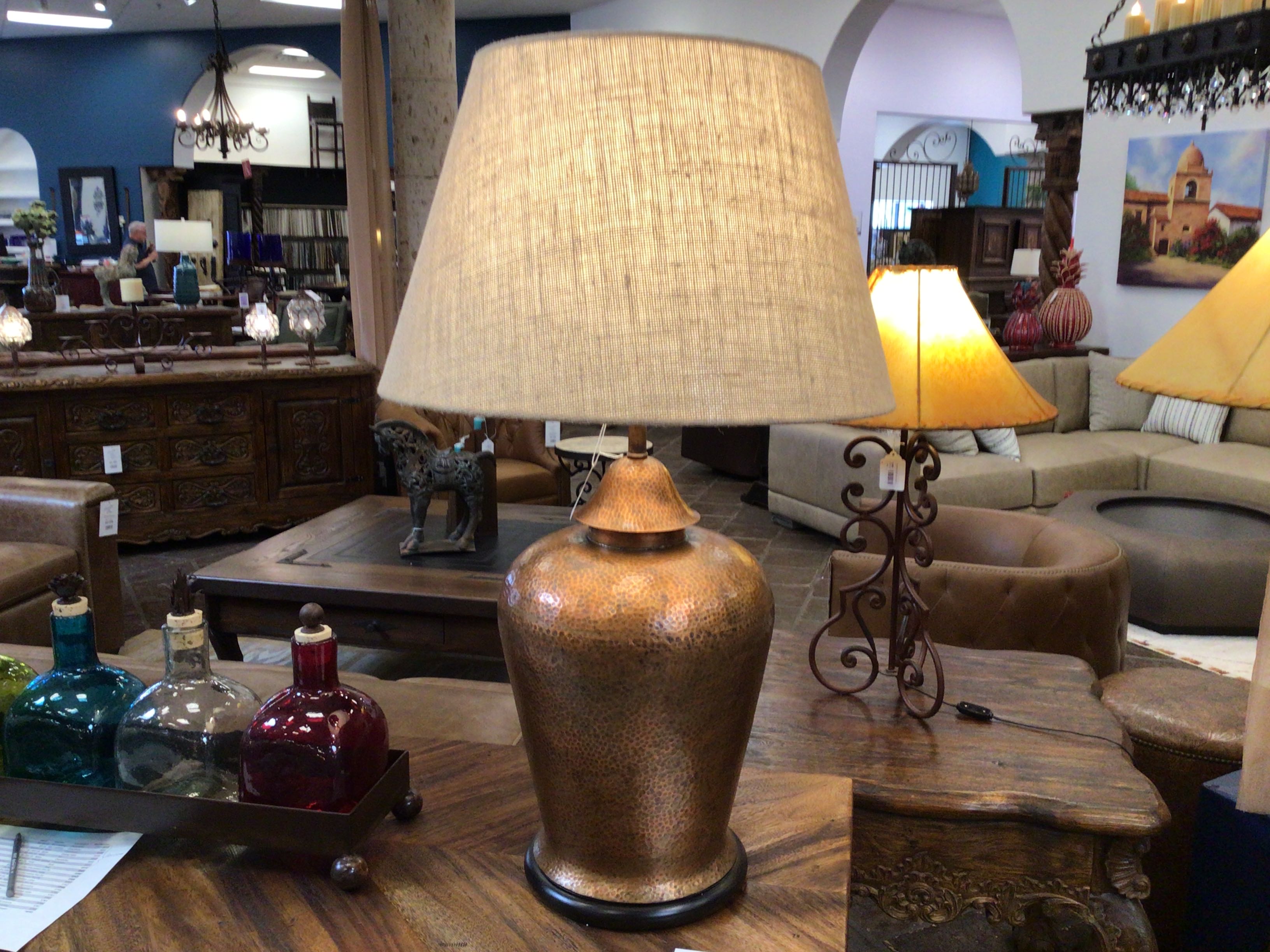 Decorative lamp with a textured shade on a wooden table in a furniture store.