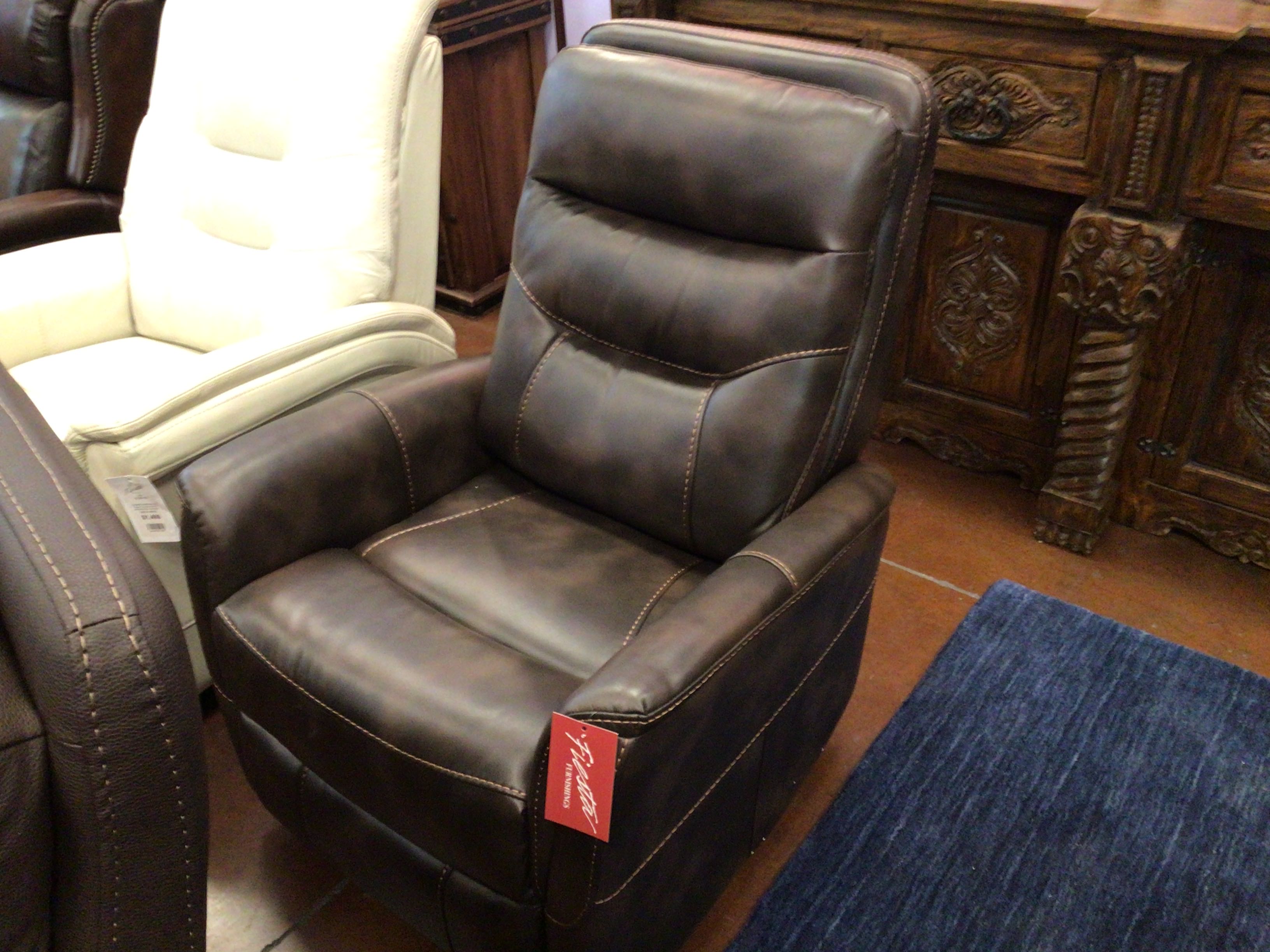 Brown leather recliner chair with a tag in a room with wooden furniture and a rug.