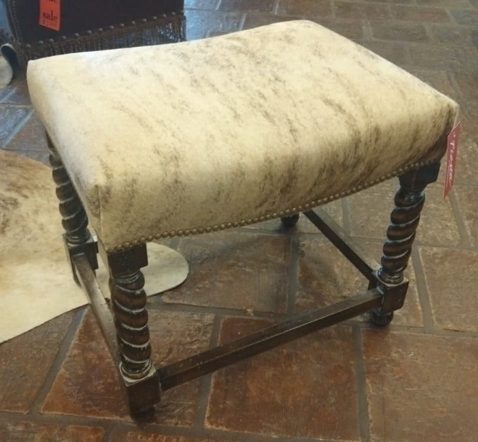 Vintage-style stool with a worn fabric seat on a tiled floor