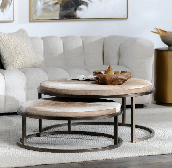 Round wooden coffee table with metal legs in a living room setting.