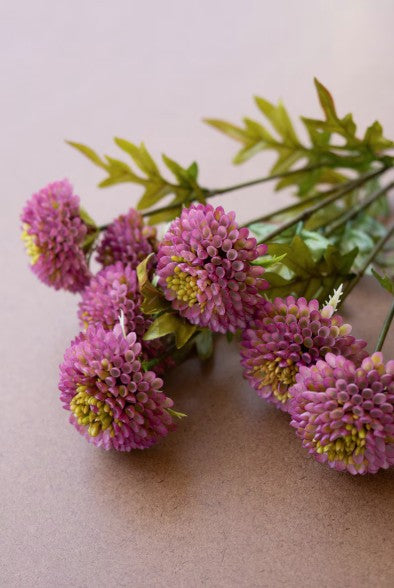 Pink artificial flowers with green leaves on a beige background