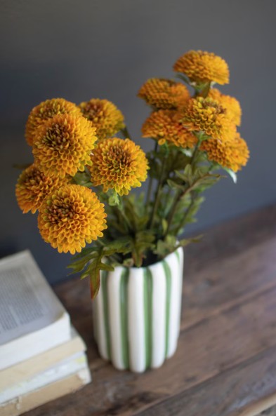Vase with yellow flowers on a wooden surface against a gray wall