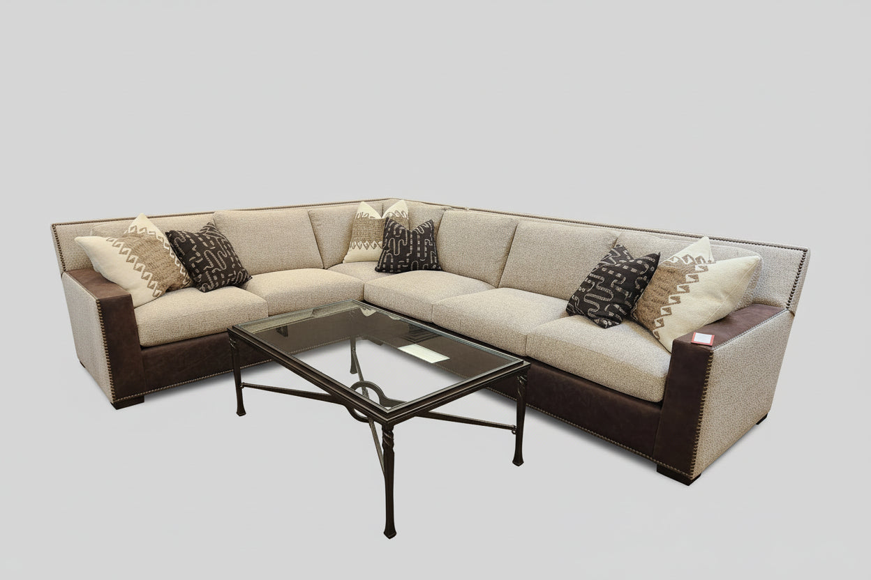 Sectional sofa with brown and beige cushions and a glass coffee table on a light gray background
