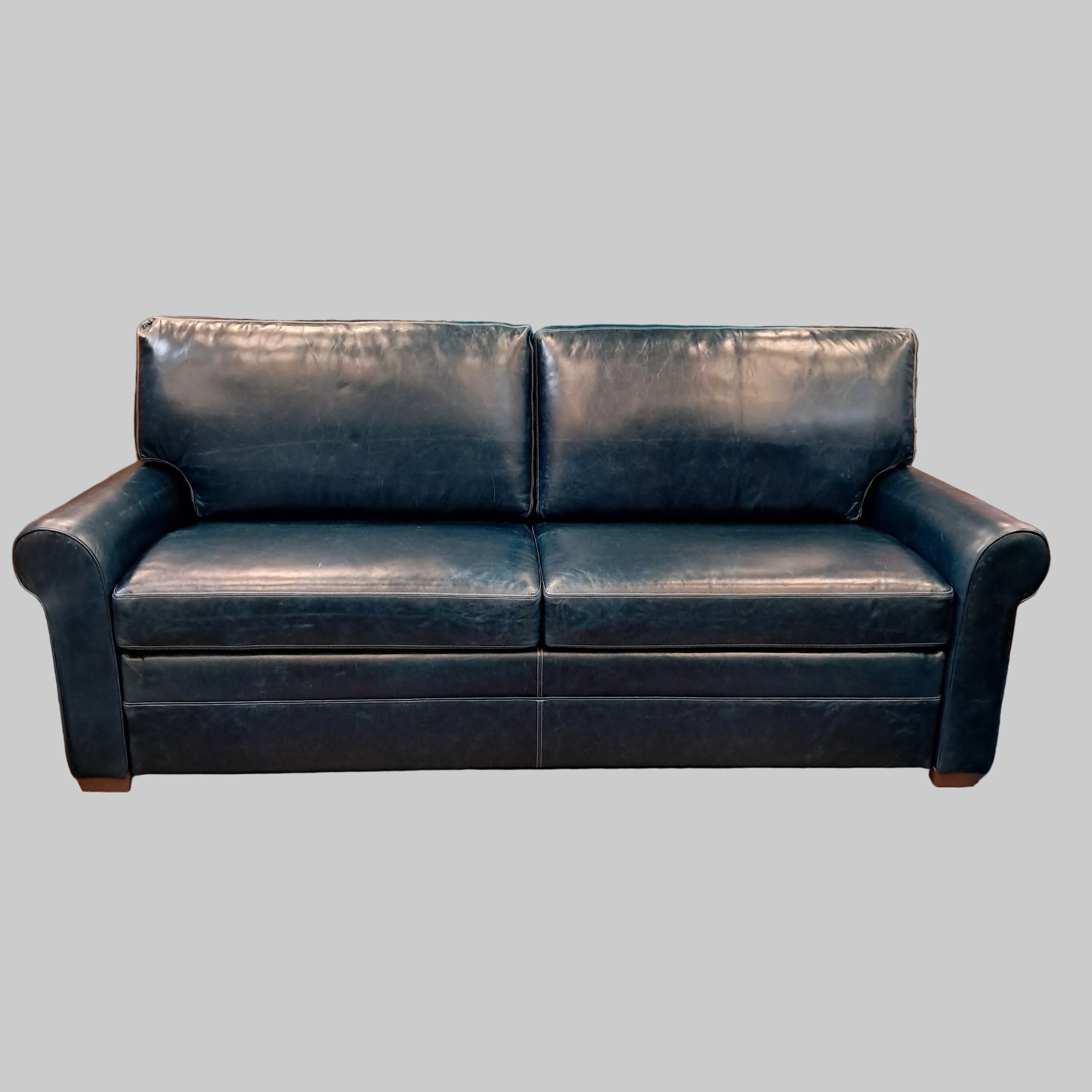 Blue leather sofa in a cluttered room with shelves and boxes.