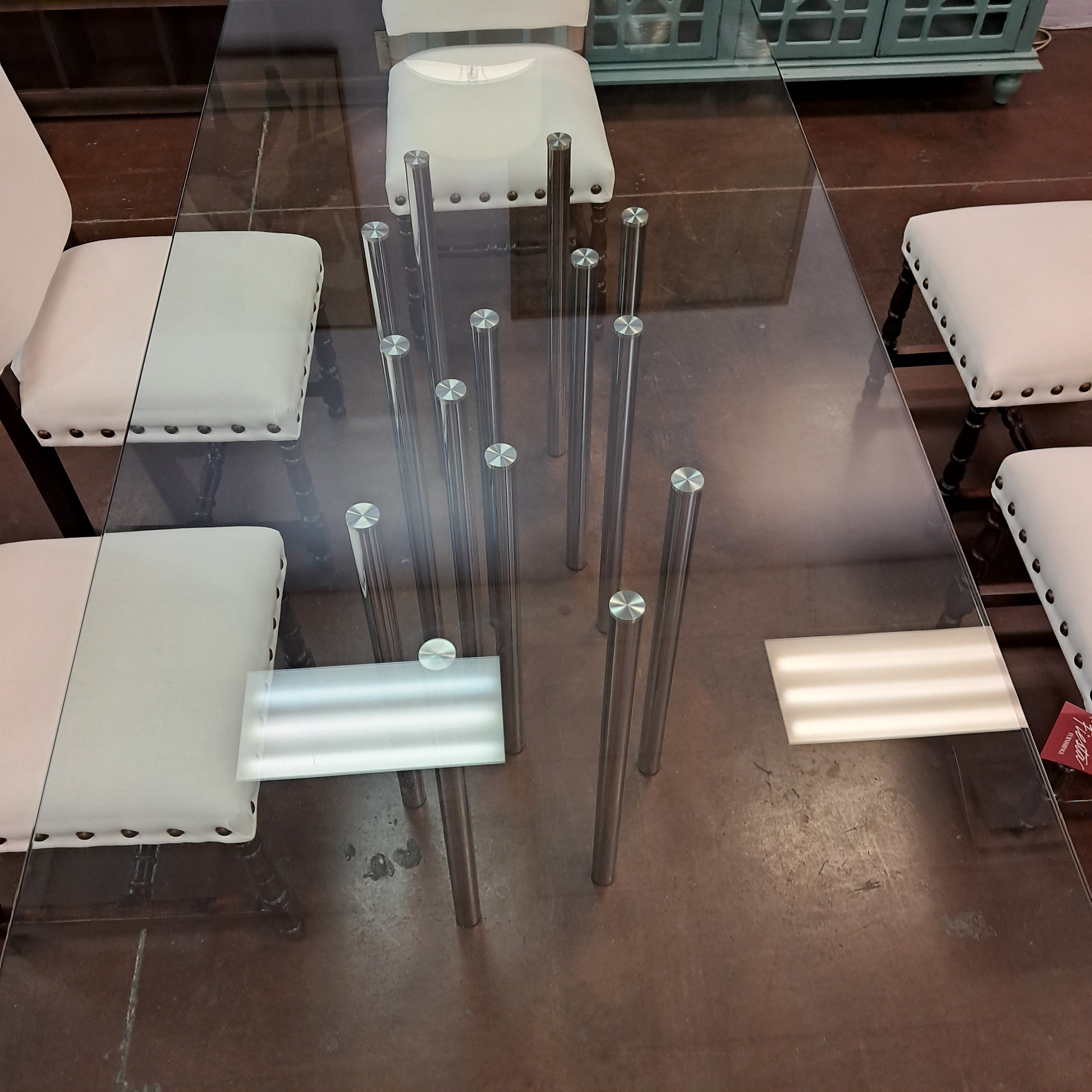 Glass dining table with metal legs and chairs in a room setting