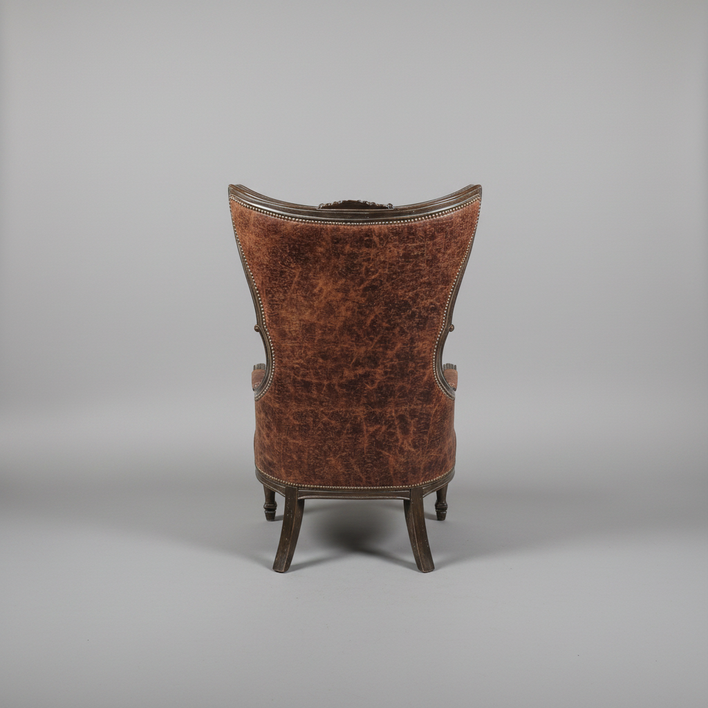 A classic wingback armchair shown from the back, featuring distressed brown leather upholstery and a dark wood frame, set against a neutral gray studio background.