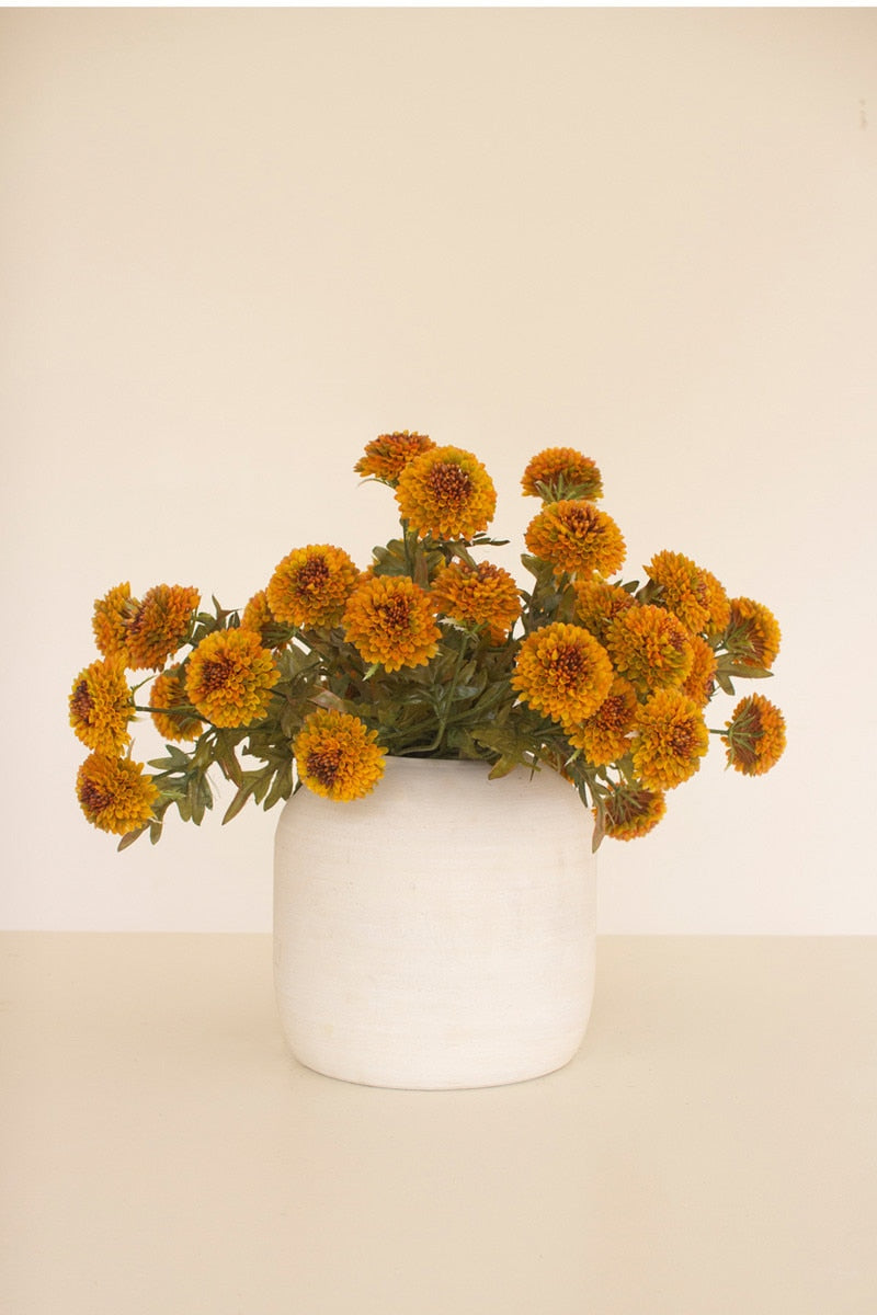 White vase with orange marigold flowers on a beige background