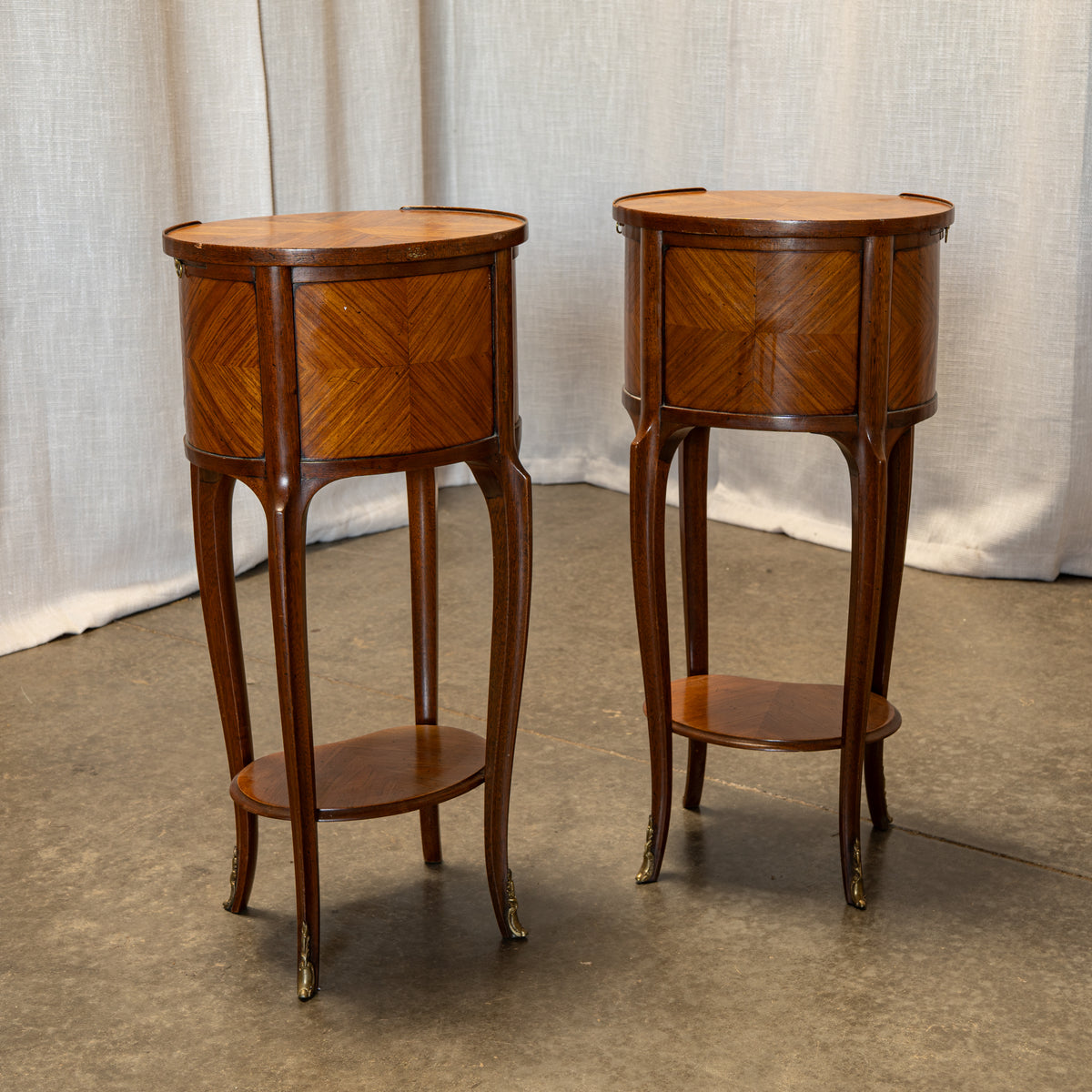 A pair of vintage mid-century wooden side tables with geometric inlay detailing, shown against a neutral draped fabric backdrop.
