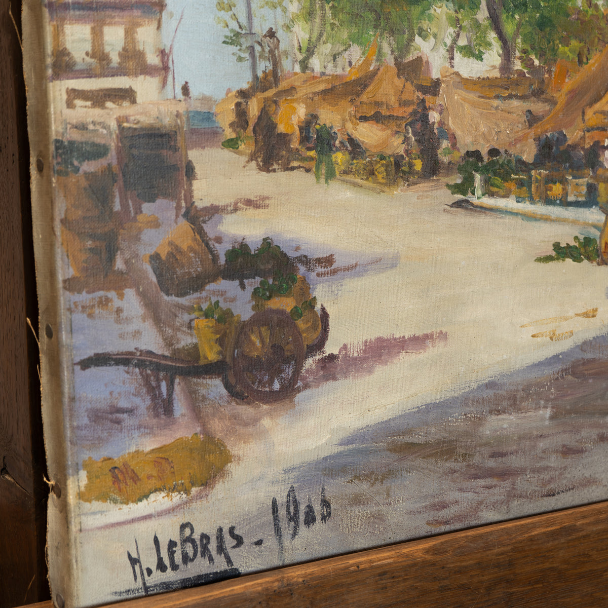 A close-up of an oil painting depicting a rustic street scene with a cart carrying green produce, market stalls, and figures, signed 'H. le Bras - 1906' in the lower left corner.
