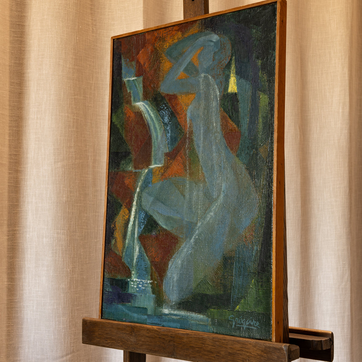 An abstract painting of a seated female figure in muted blue, green, brown, and orange tones, displayed on a wooden easel against a beige curtain backdrop.