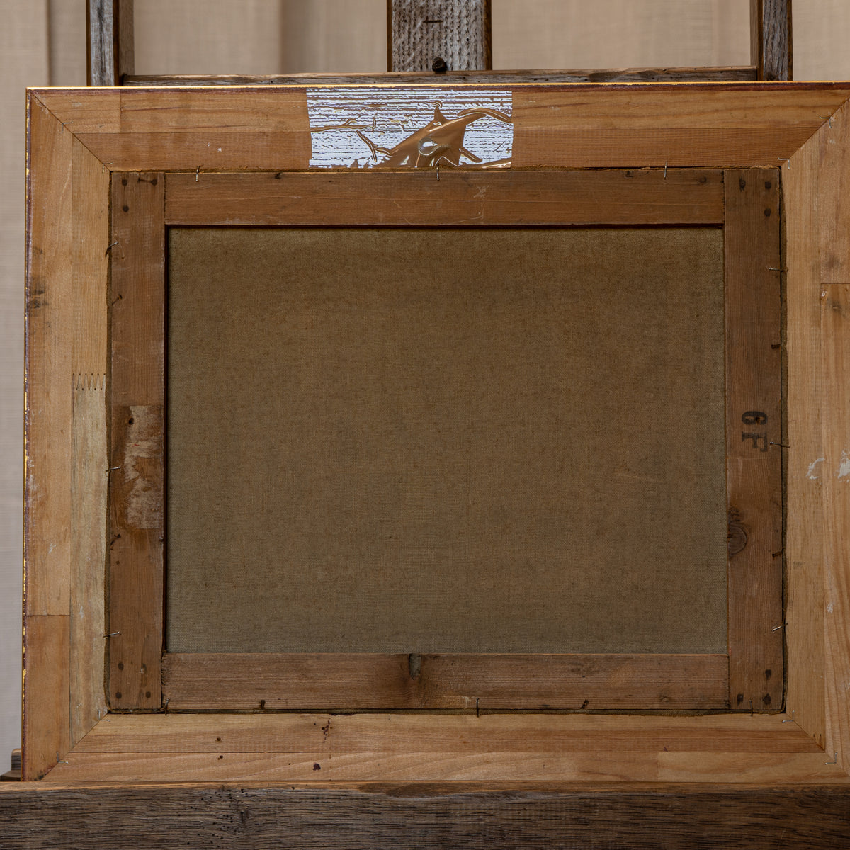 The back side of a rustic wooden picture frame, showing the canvas backing and construction details.