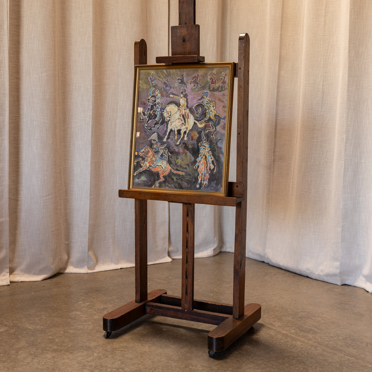 A dark brown wooden easel on casters, holding a framed painting of a historical battle scene with mounted soldiers, set against a neutral beige curtain backdrop.