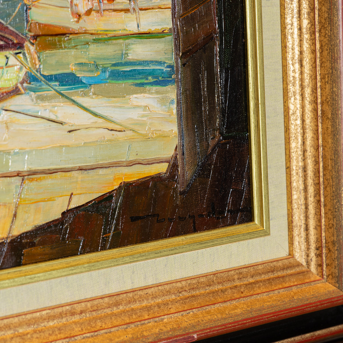 Close-up of a framed painting showing textured impasto brushstrokes in cream, blue, yellow, and dark brown, with a gold-toned frame and mat.