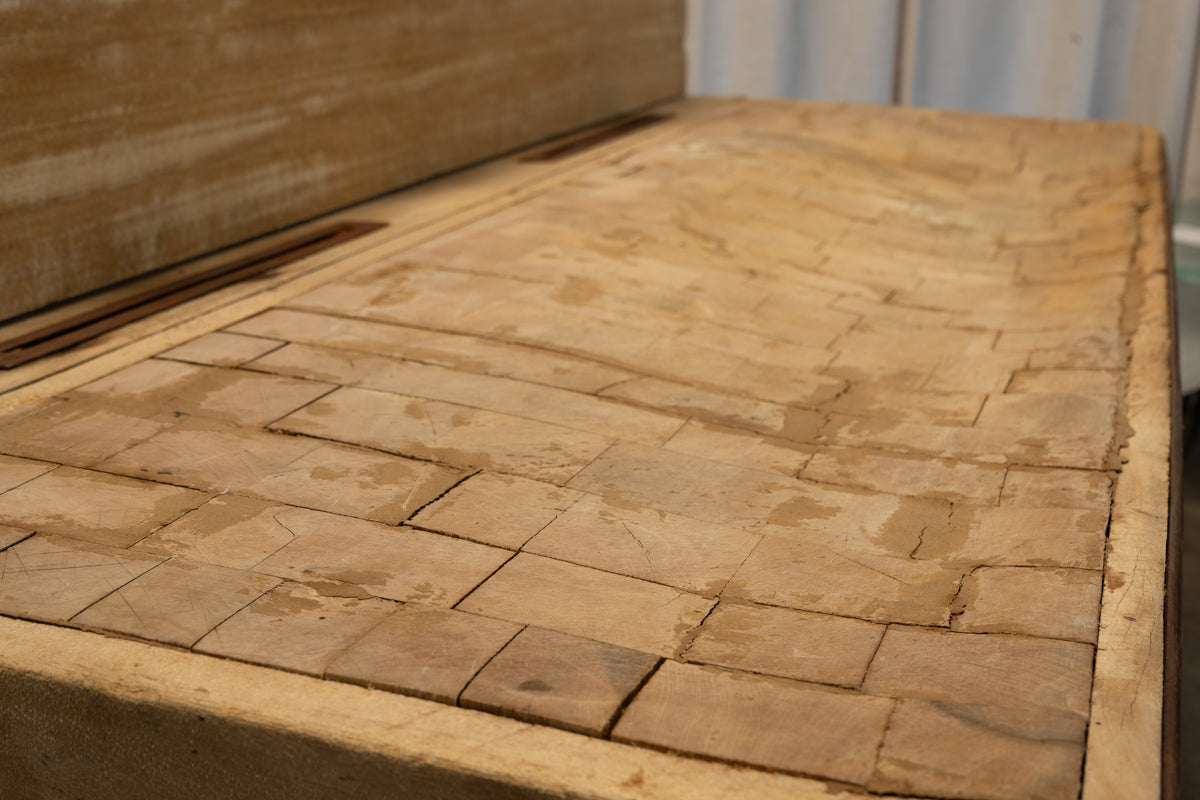 A close-up view of a rustic wooden box or tray with a textured, weathered stone or tile-like pattern on its lid, set against a neutral background.