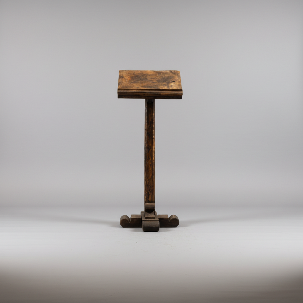 A small dark brown wooden stand or lectern with a rectangular top, vertical post, and cross-shaped base, photographed against a light gray studio background.