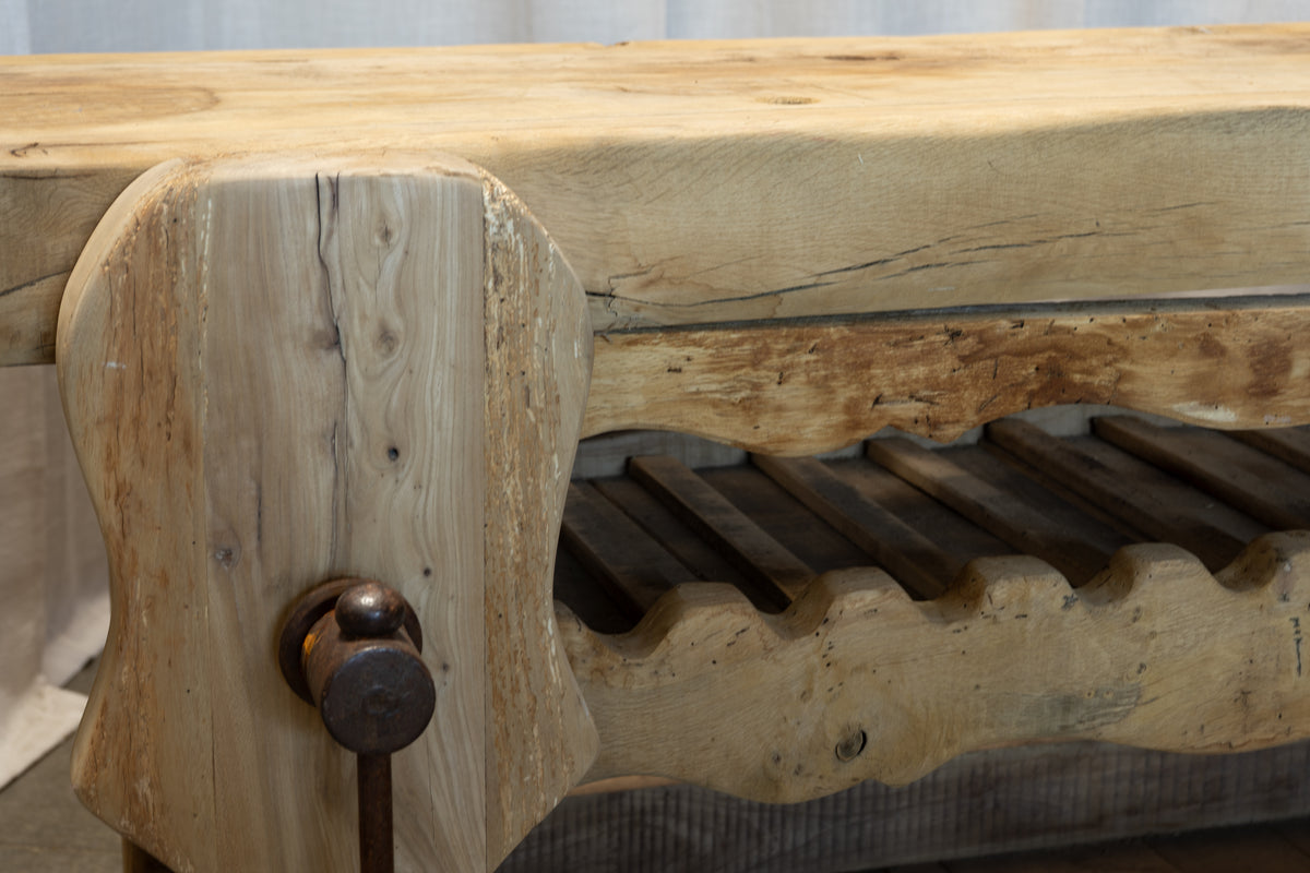 Close-up of a rustic wooden wine rack with a thick natural wood top and a dark metal pull knob on the front.