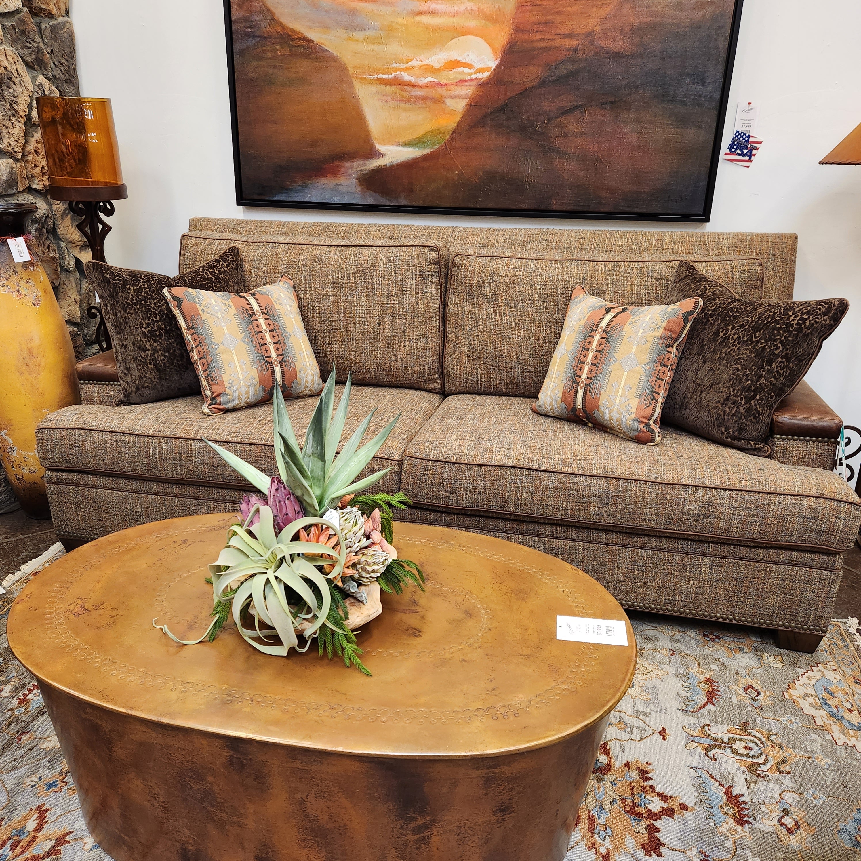 Living room with a brown sofa, decorative pillows, and a gold coffee table with plants.