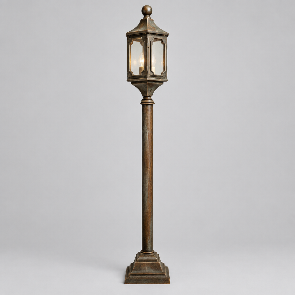 A tall decorative outdoor-style lantern post with a dark bronze finish and a lit candle-style bulb inside, centered on a light gray studio background.
