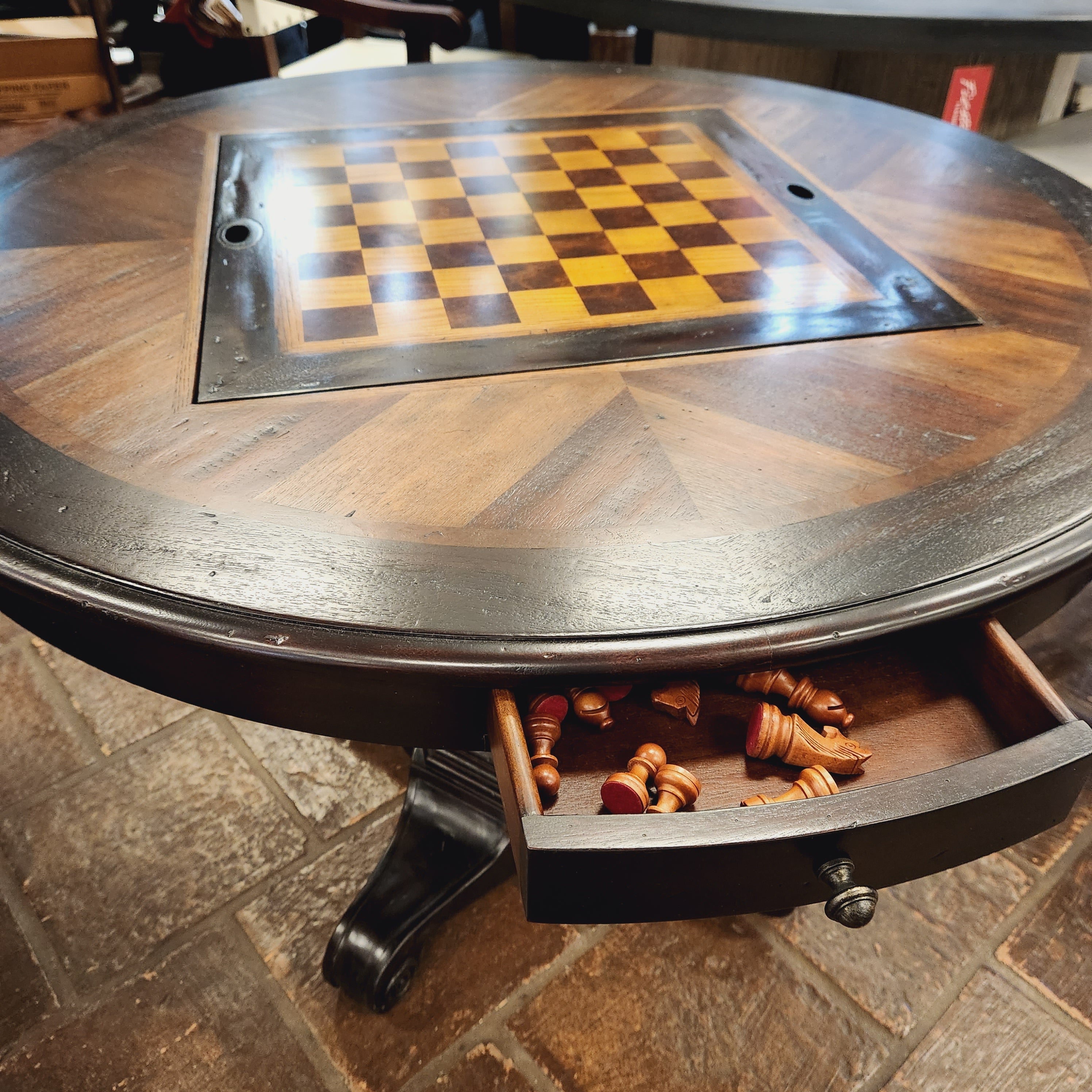 Wooden wall-mounted chess board with checkered surface and storage drawer for chess pieces.